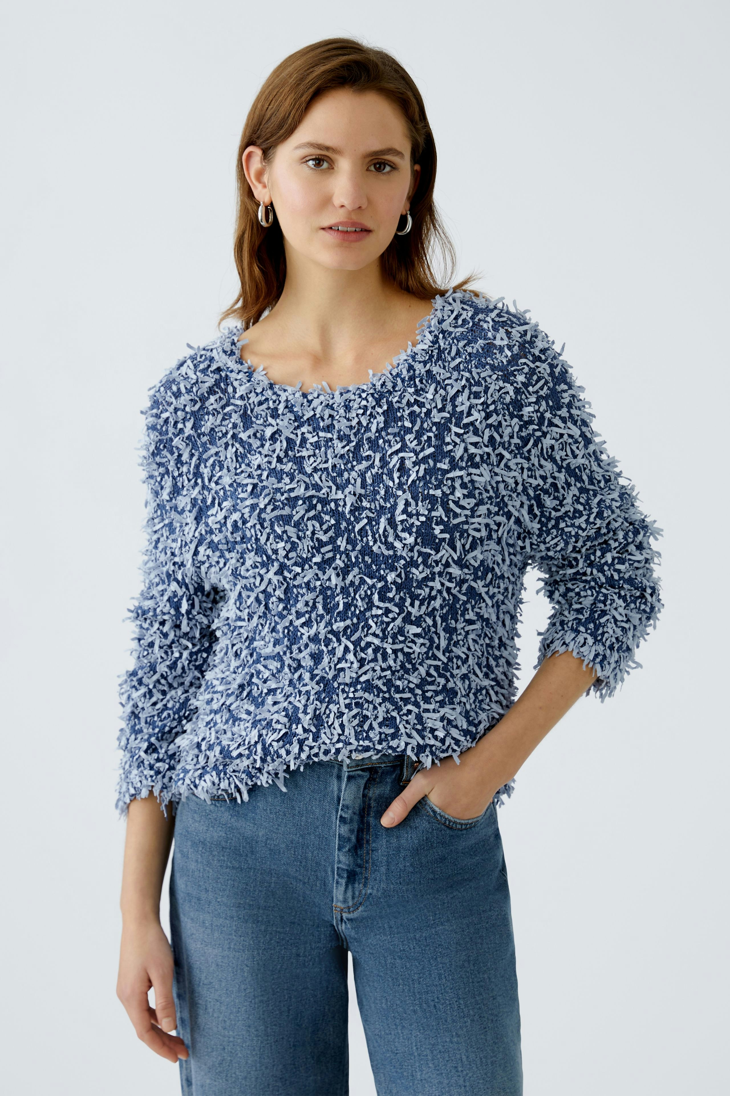 Cozy women's pullover: A woman in a fluffy blue pullover paired with denim jeans.