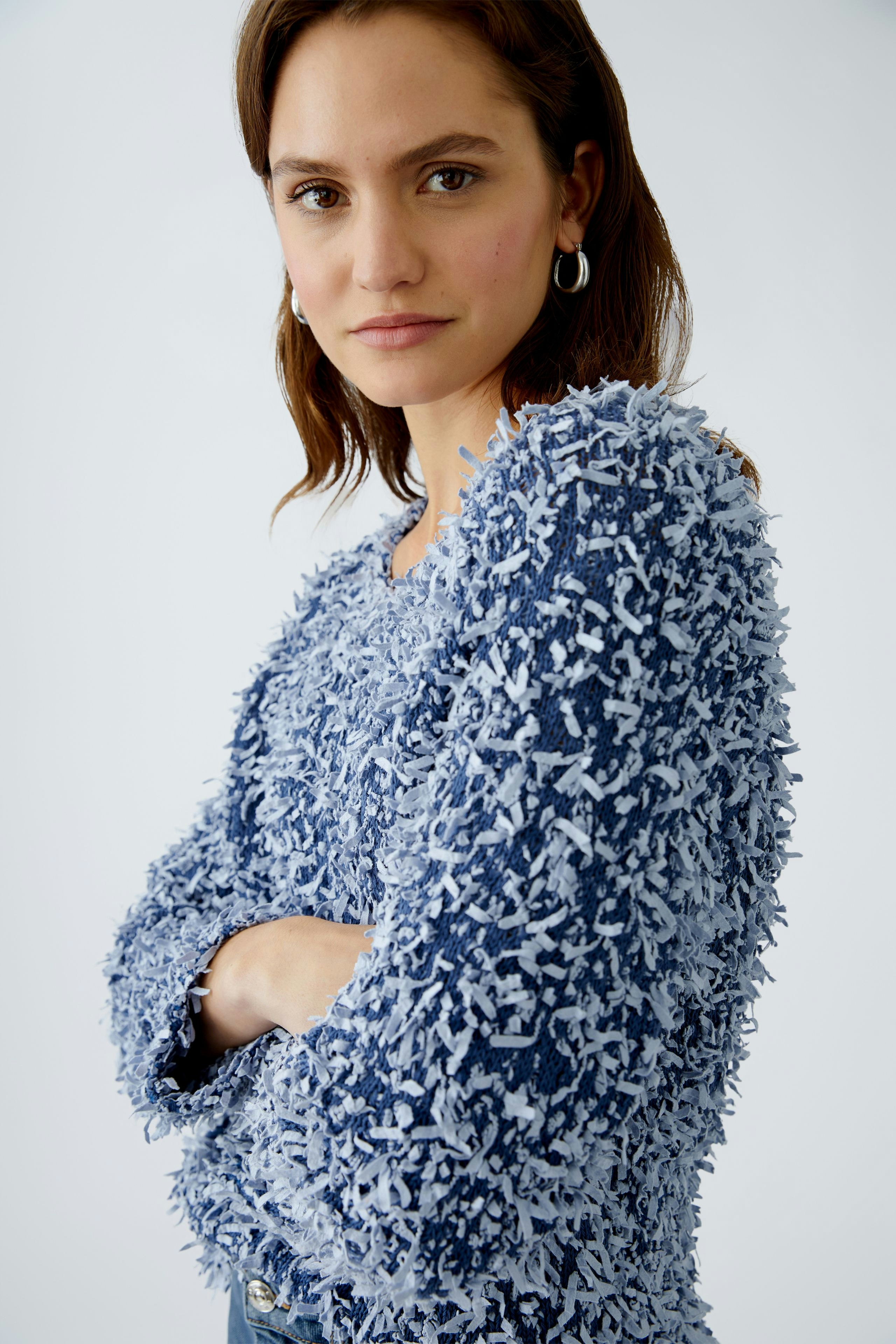 Stylish women's pullover: A woman in a textured blue pullover with a relaxed fit.