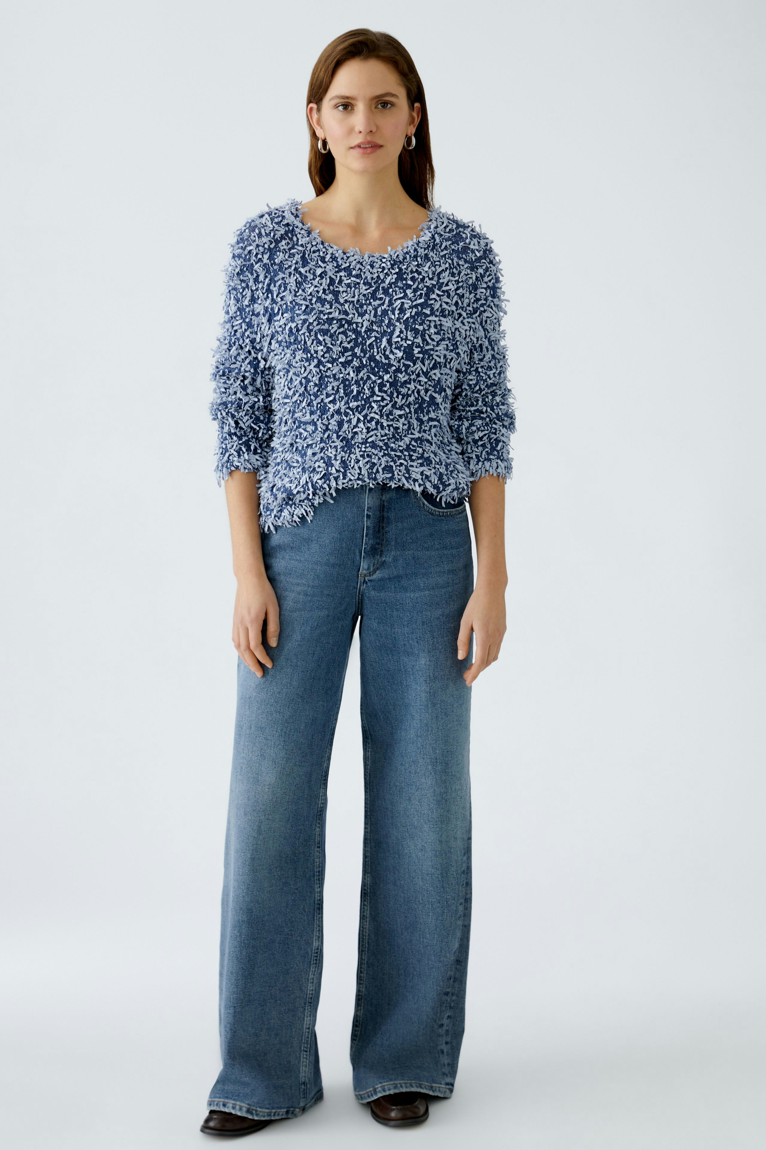 Stylish women's pullover: A woman in a fluffy blue pullover paired with wide-leg jeans.
