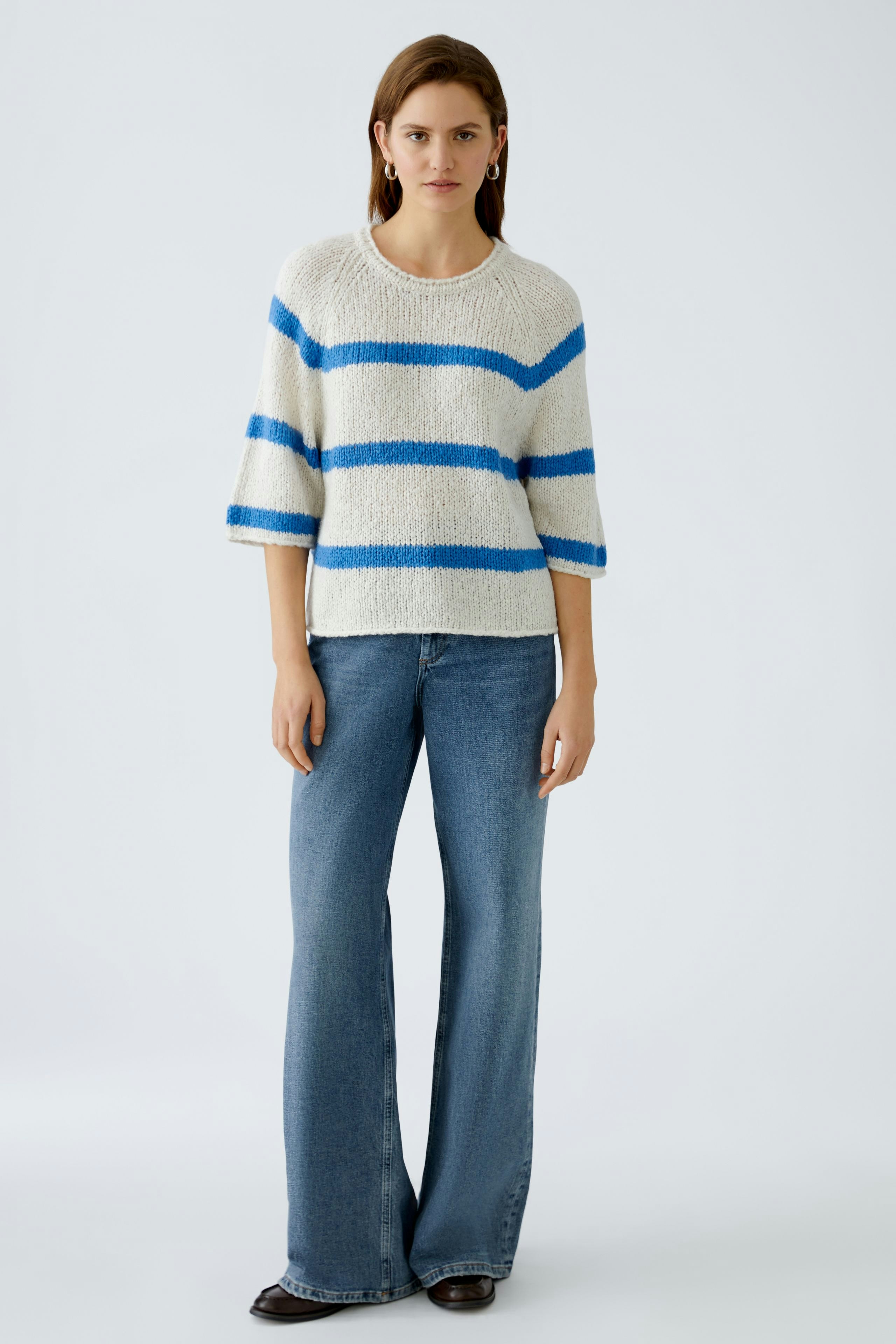 Damen-Pullover: Junge Frau im gestreiften, bequemen Pullover mit kurzen Ärmeln und lässigen Jeans.