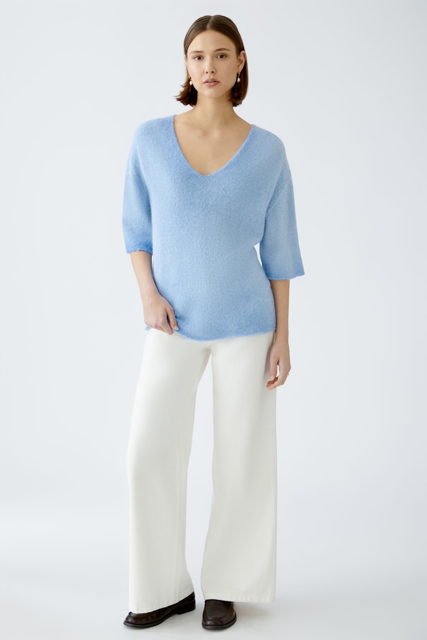 Stylish women's pullover: A woman in a light blue, soft pullover with a V-neck and relaxed fit.