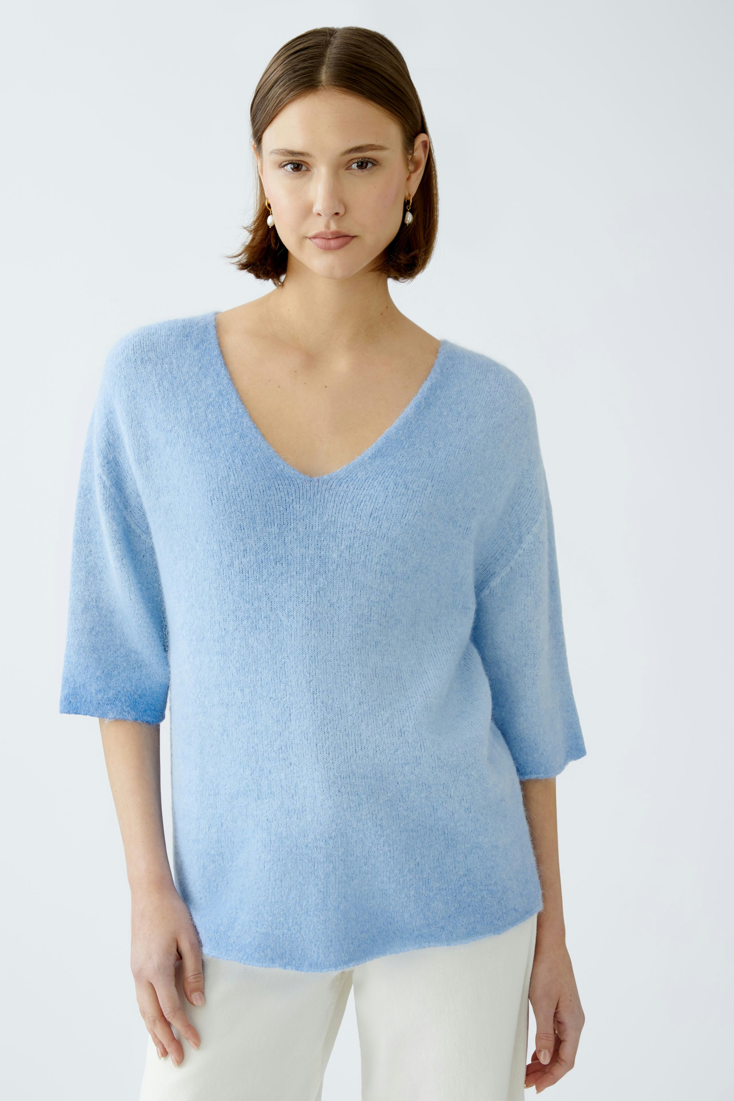 Helle Damen-Pullover: Frau in einem blauen, weichen Pullover mit V-Ausschnitt und kurzen Ärmeln.
