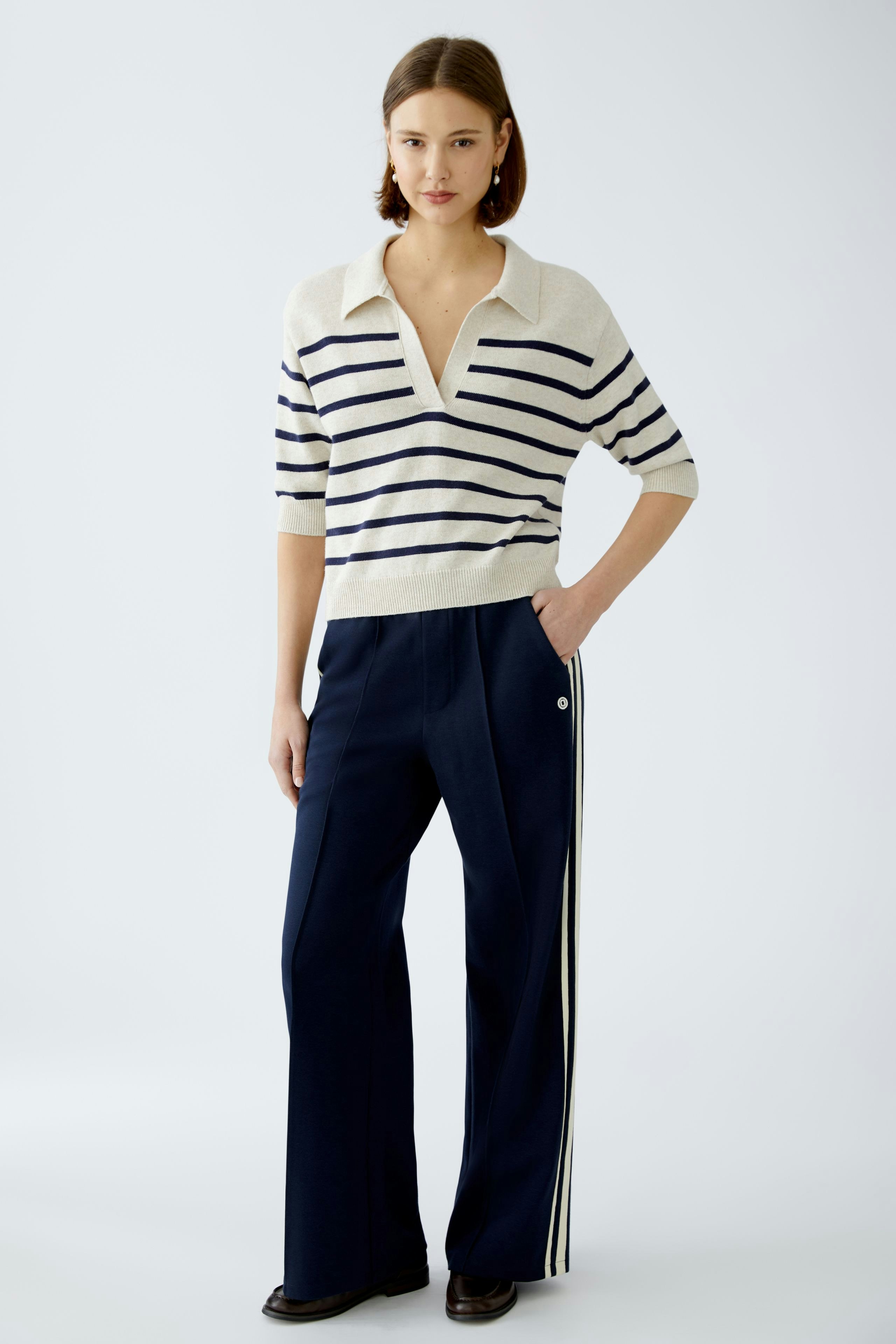 Damen-Pullover: Junge Frau im gestreiften Pullover mit V-Ausschnitt und lässiger Hose.