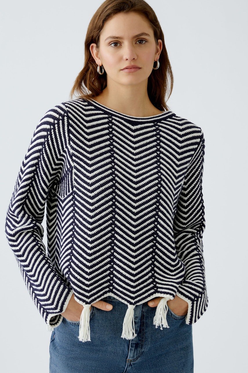 Stylish women's pullover: A woman in a navy and white patterned pullover with tassels.