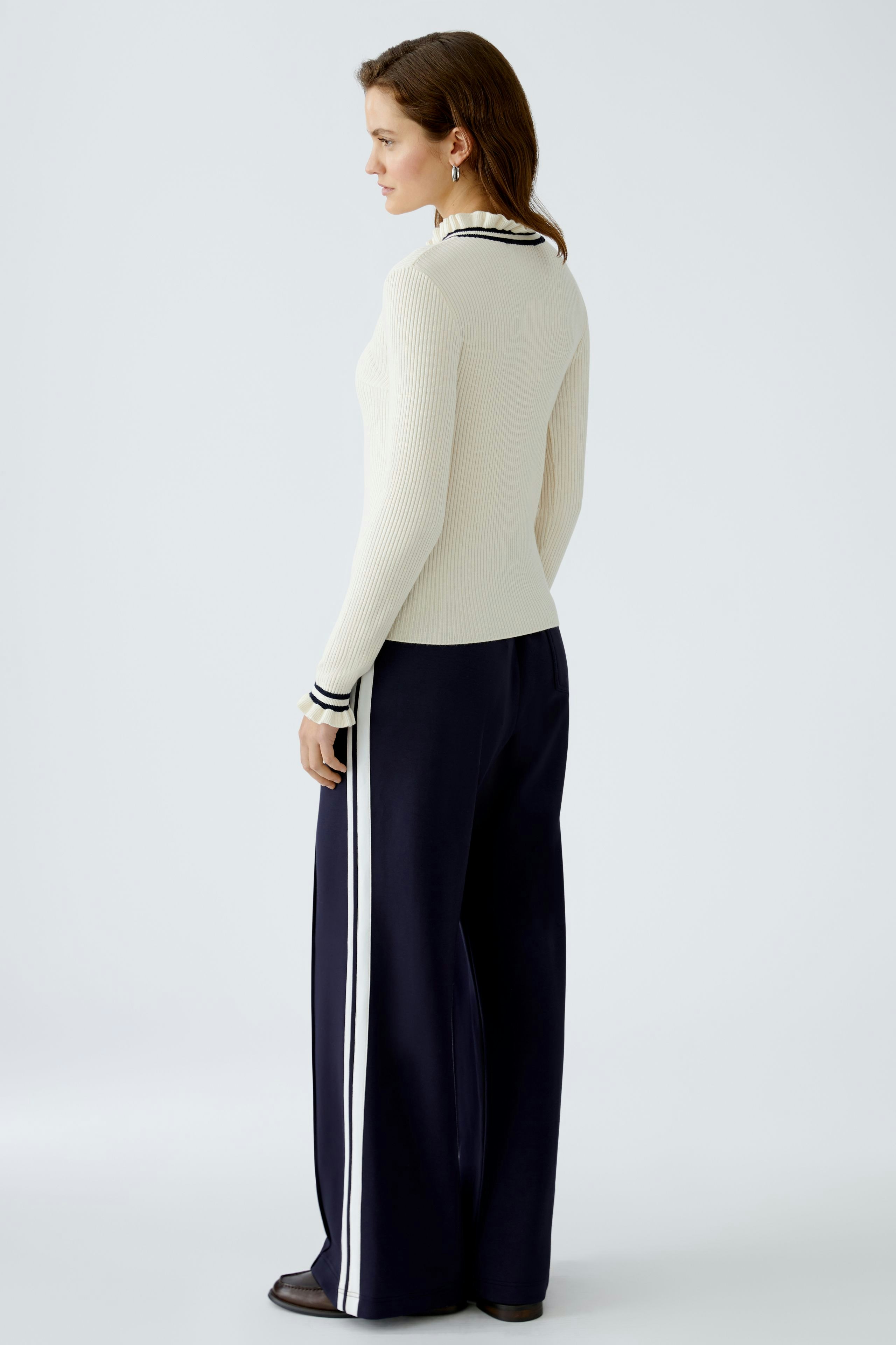 Eleganter Damen-Pullover in Creme mit Streifen, lässig kombiniert mit weiten Hosen.