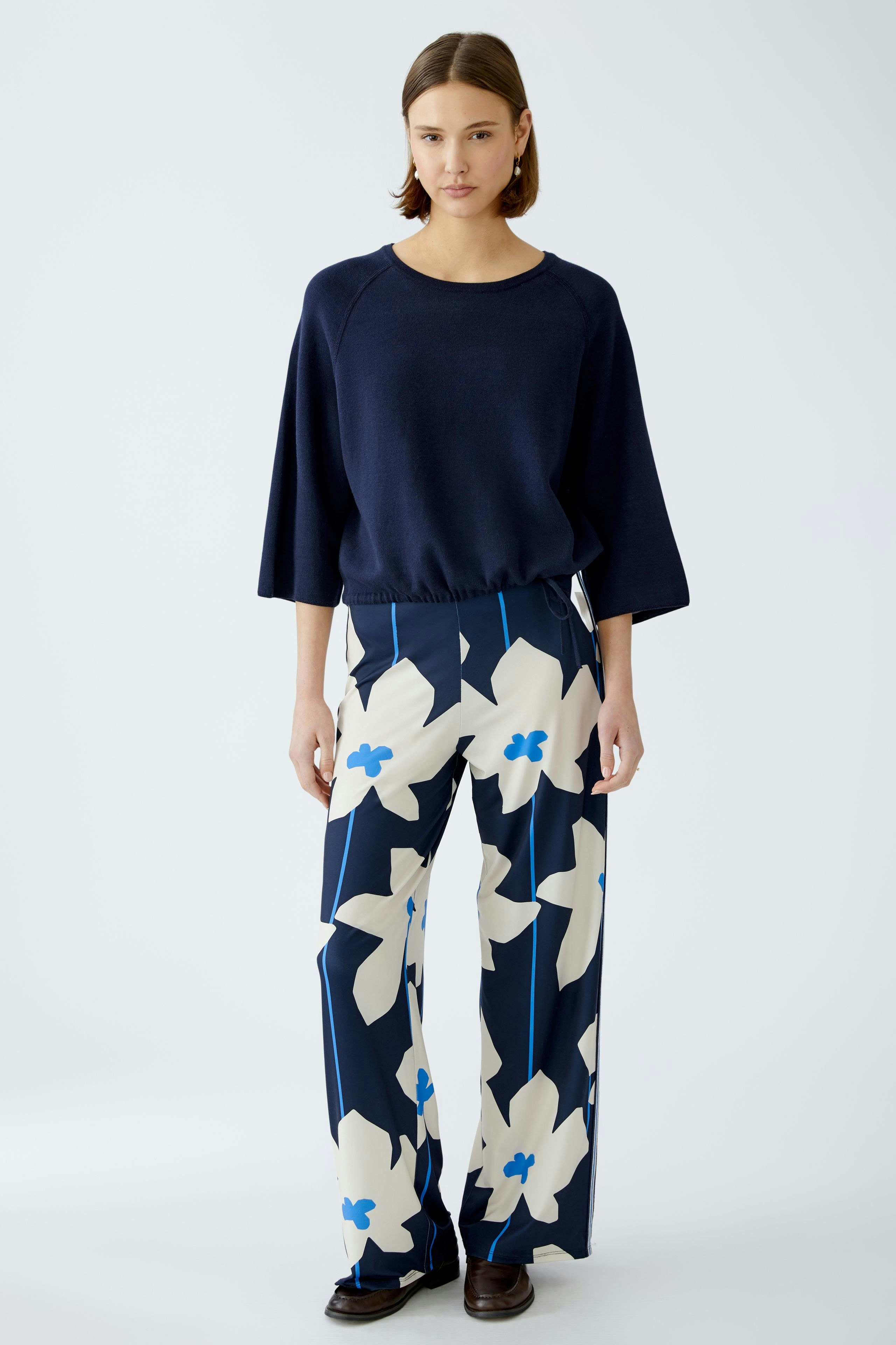 Stylish women's pullover: A woman in a navy pullover paired with floral wide-leg pants.