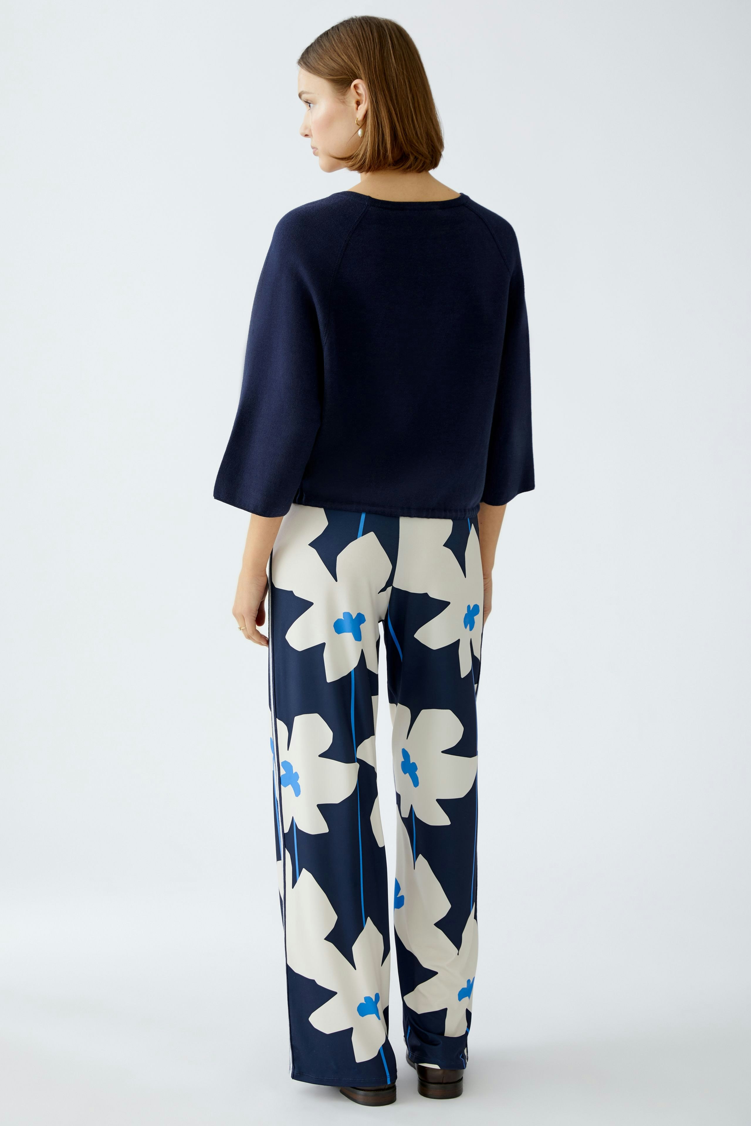Stylish women's pullover: A woman in a navy pullover paired with floral wide-leg pants.