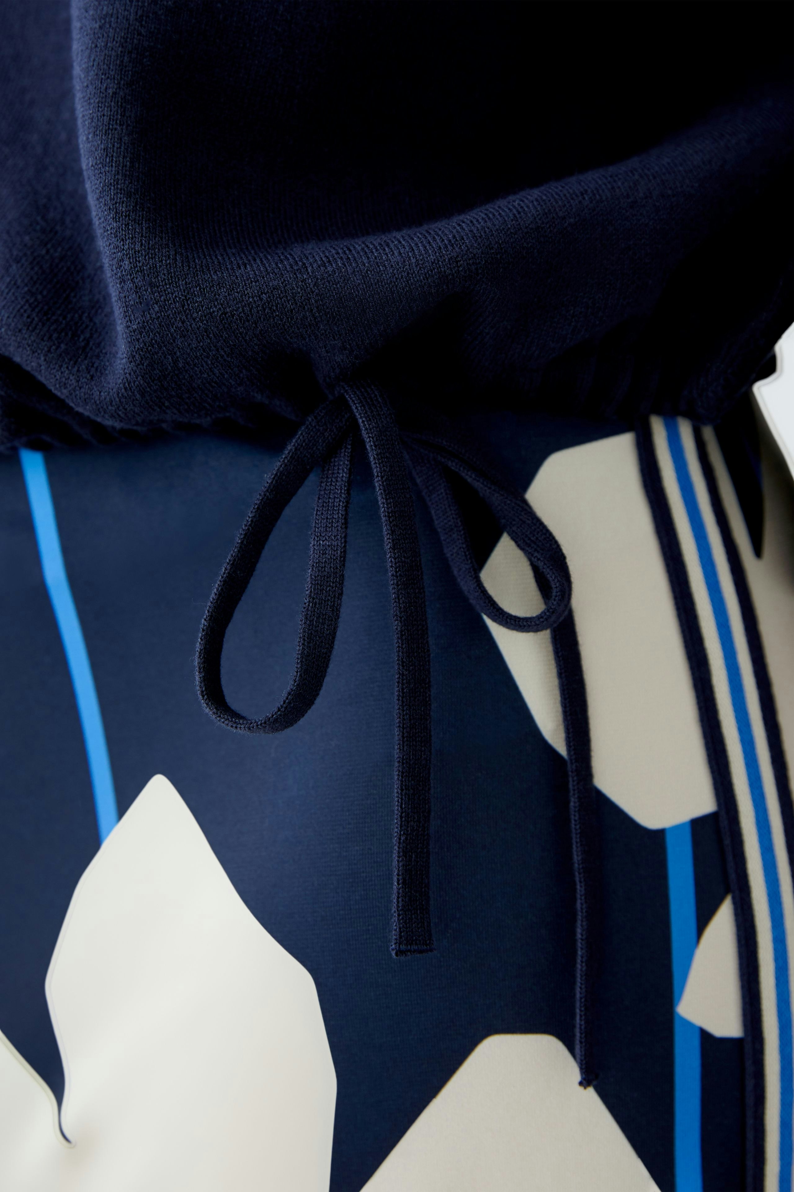 Stylish women's pullover with a drawstring detail, paired with patterned pants for a chic look.