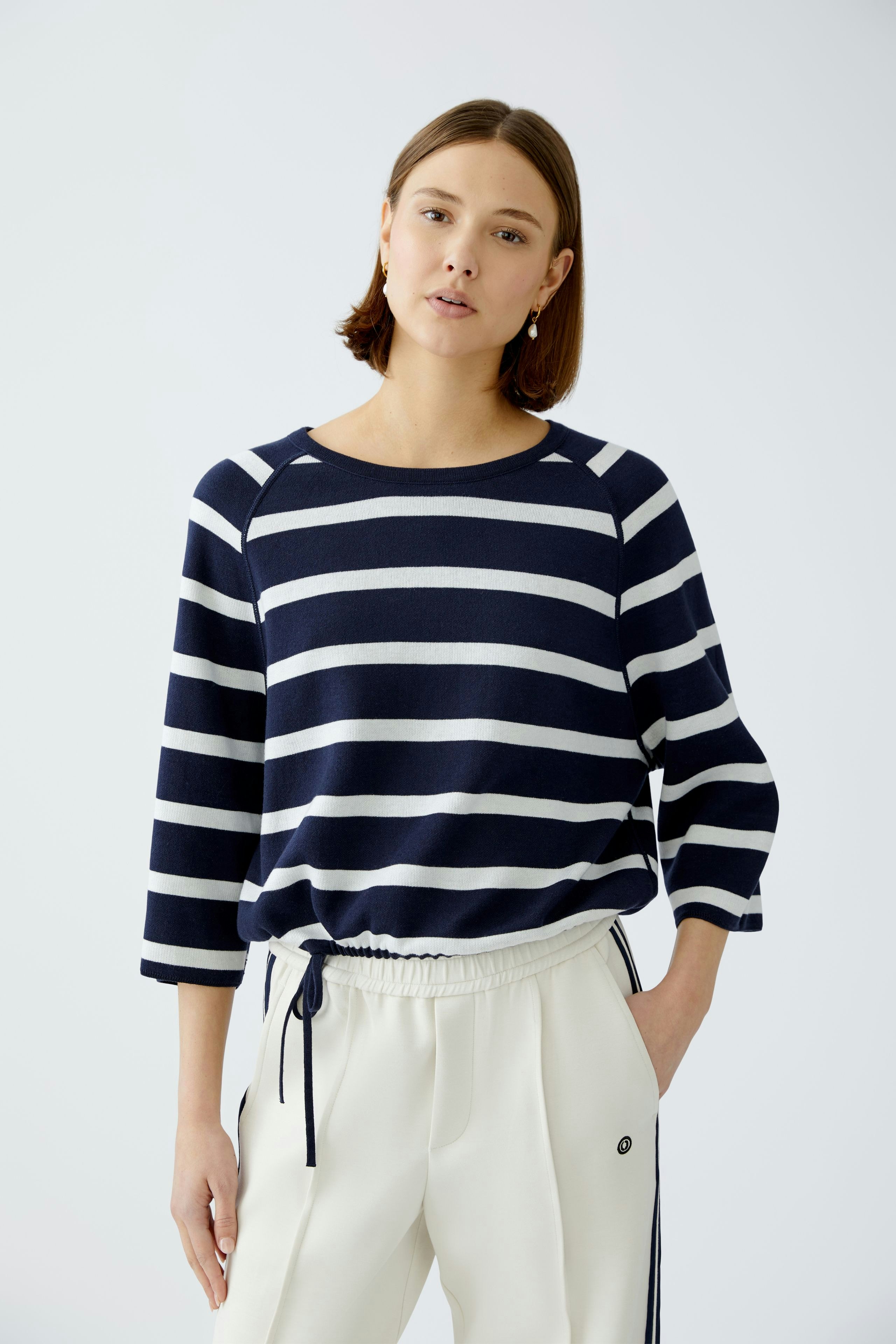 Stylish women's pullover: A woman in a navy and white striped pullover, paired with relaxed trousers.
