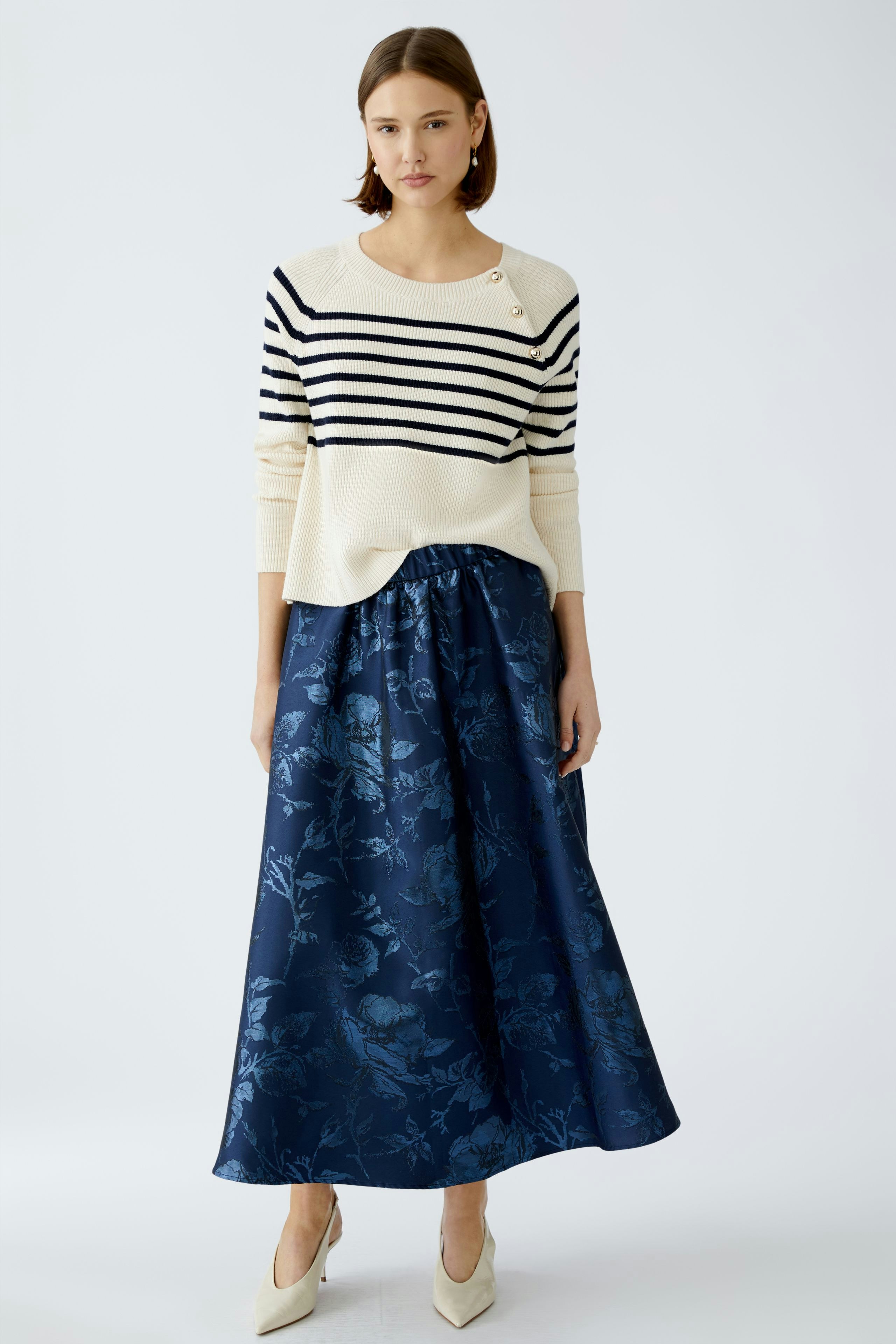 Stylish women's pullover: A woman in a striped pullover paired with a floral skirt, exuding elegance.