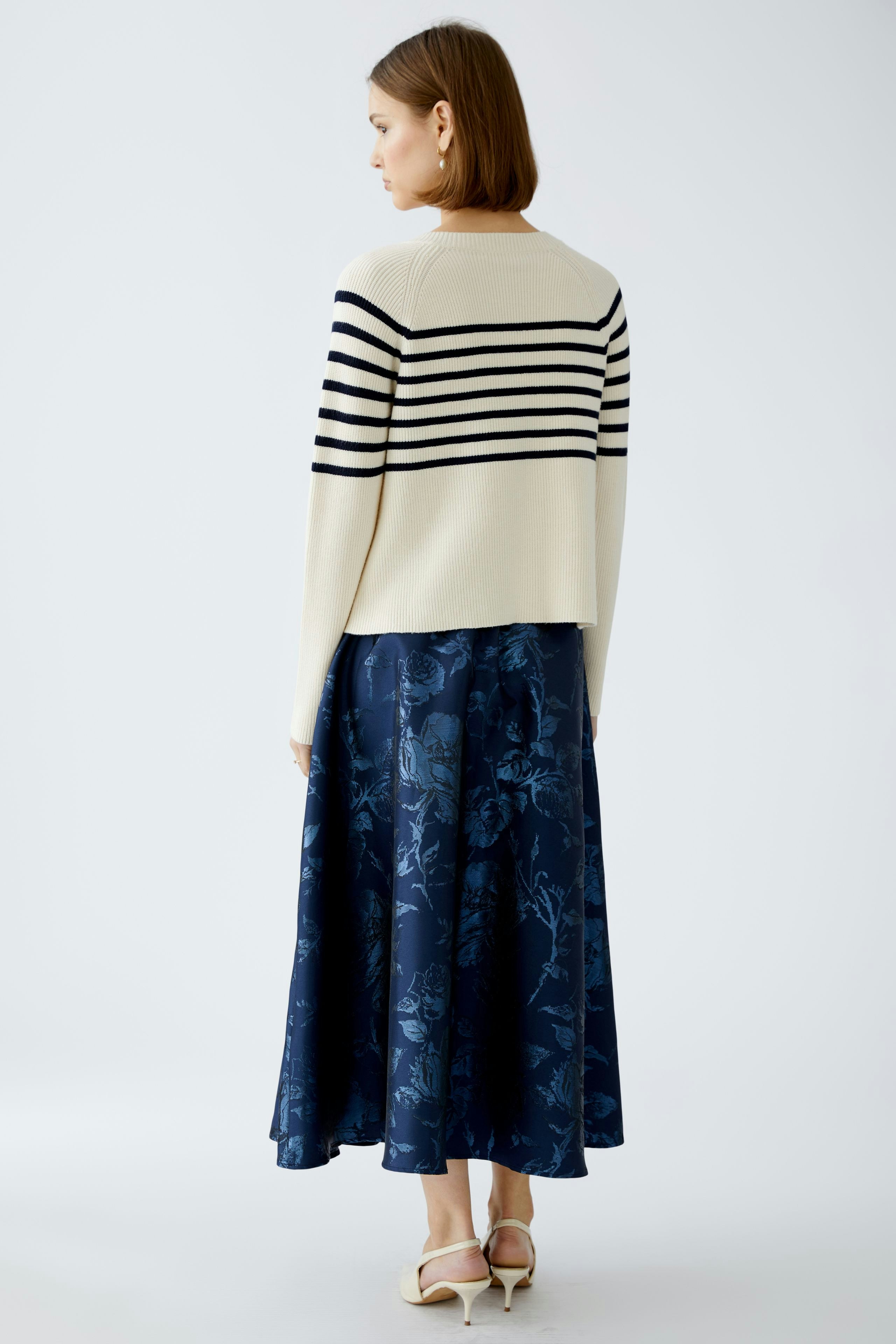 Stylish women's pullover: A woman in a striped pullover paired with a floral skirt, showcasing a chic look.
