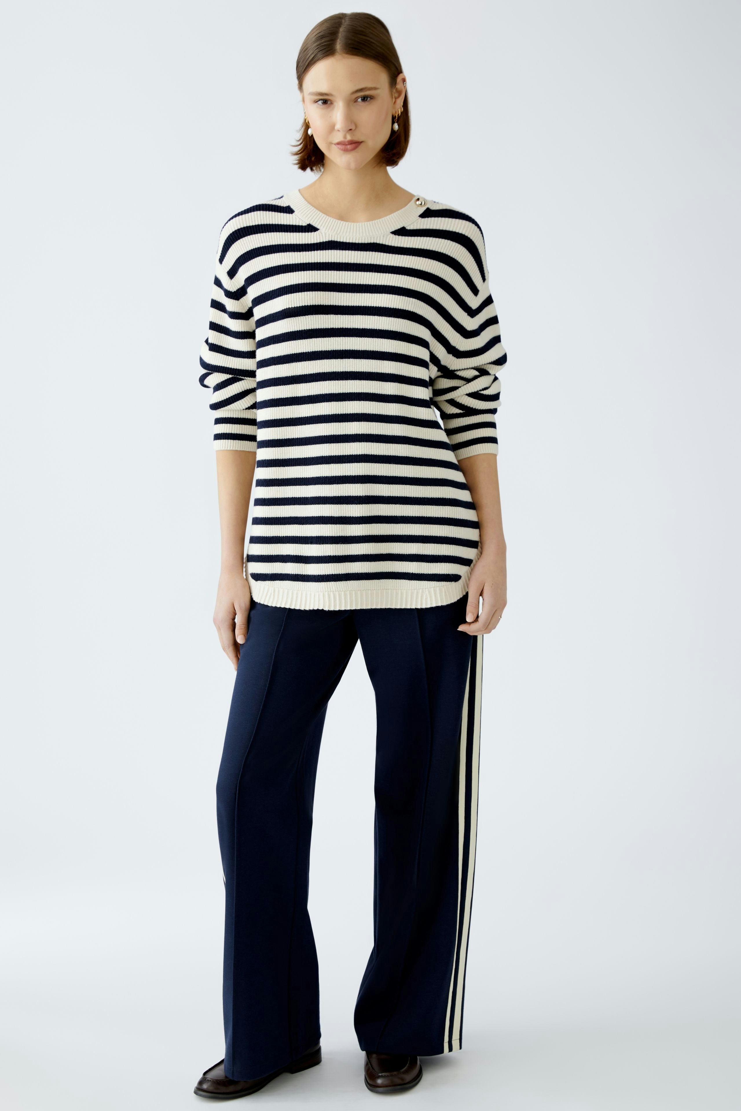 Damen-Pullover: Junge Frau in gestreiftem Pullover mit lässigem Schnitt und bequemen Hosen.