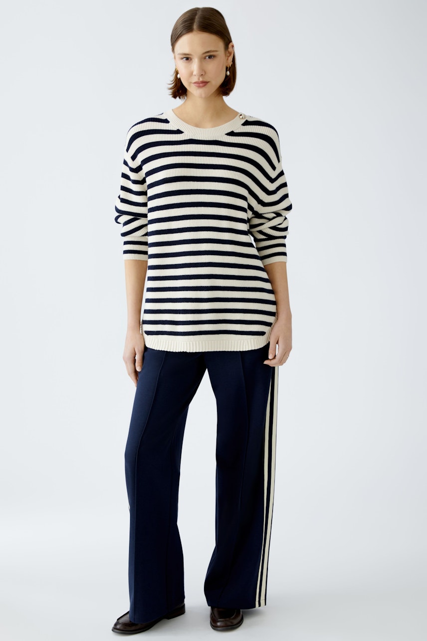 Stylish women's pullover: A woman in a striped pullover paired with navy pants, exuding casual elegance.