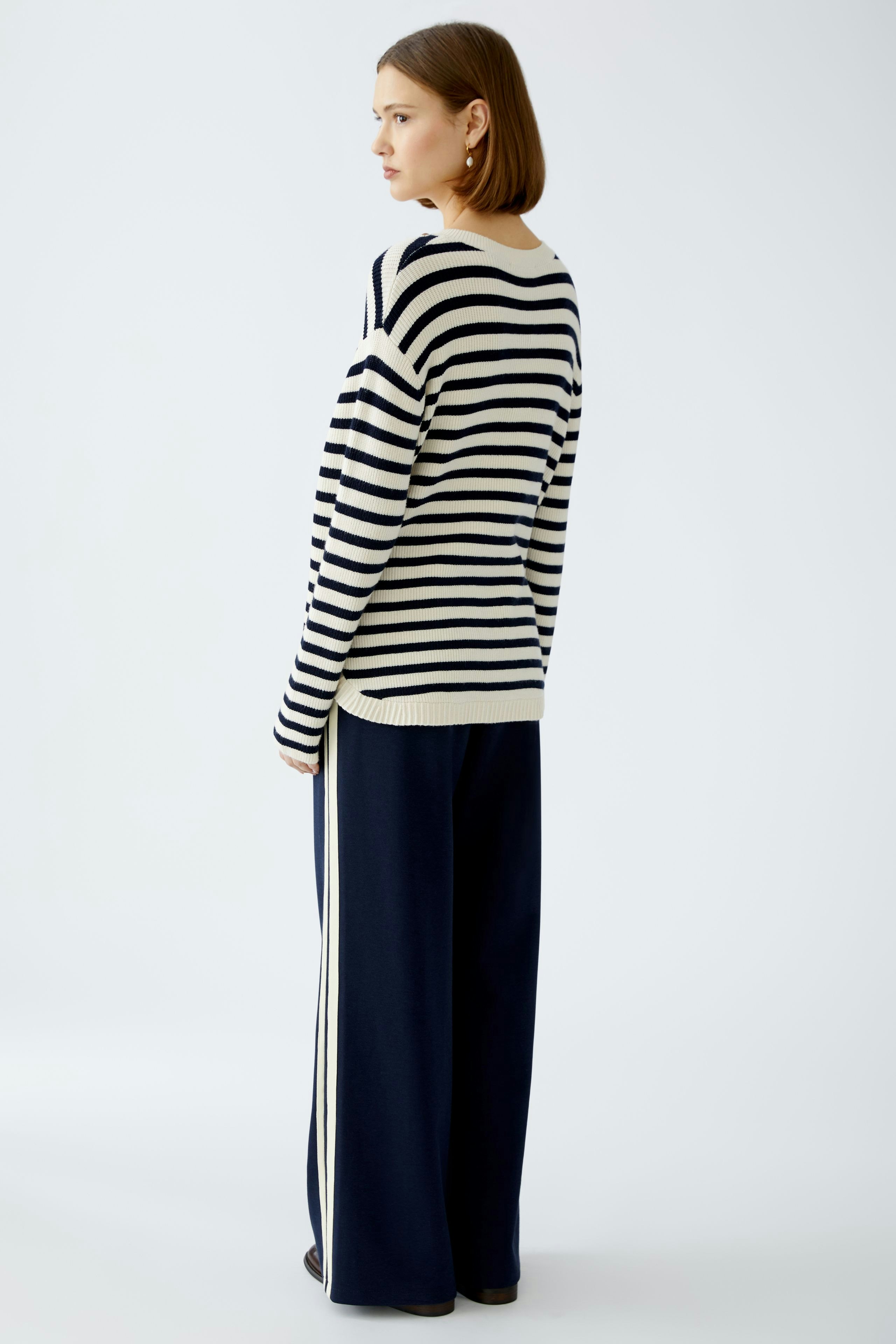 Damen-Pullover: Frau in gestreiftem Pullover mit lässigem Schnitt und bequemen Hosen von hinten.