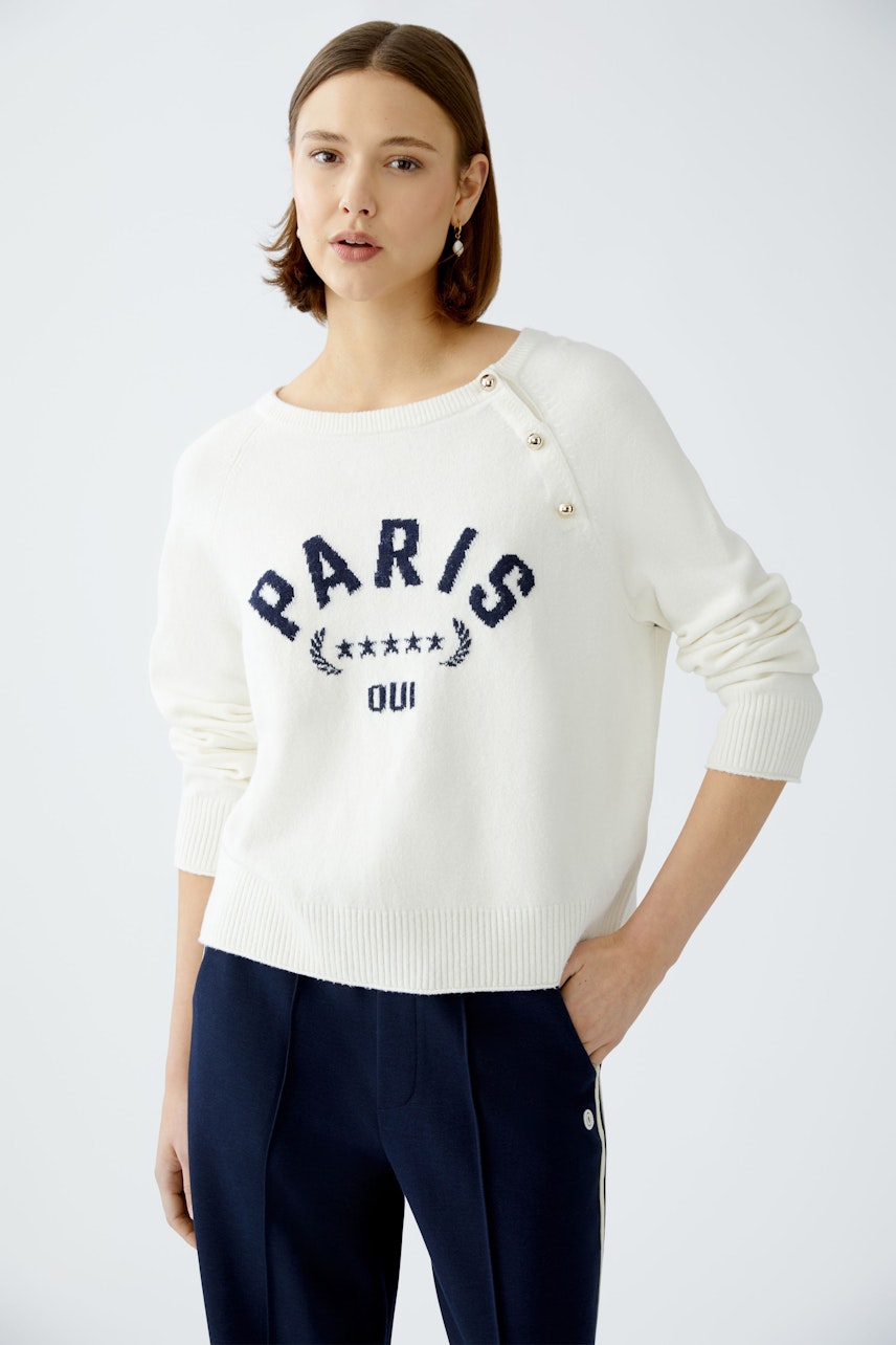 Damen-Pullover in Weiß mit Paris-Print und Knöpfen, lässig kombiniert mit sportlicher Hose.