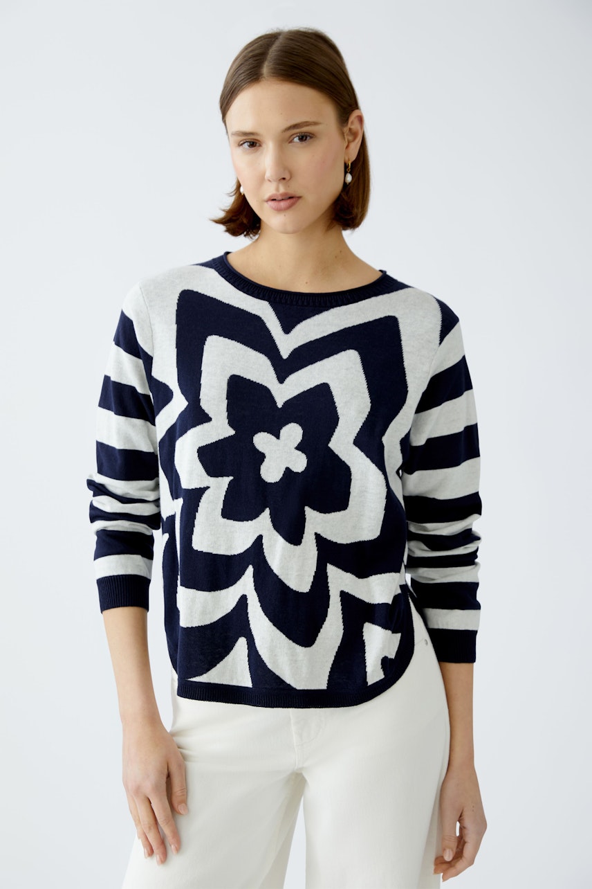 Damen-Pullover: Frau in gestreiftem Pullover mit floralem Muster, lässig und modern.