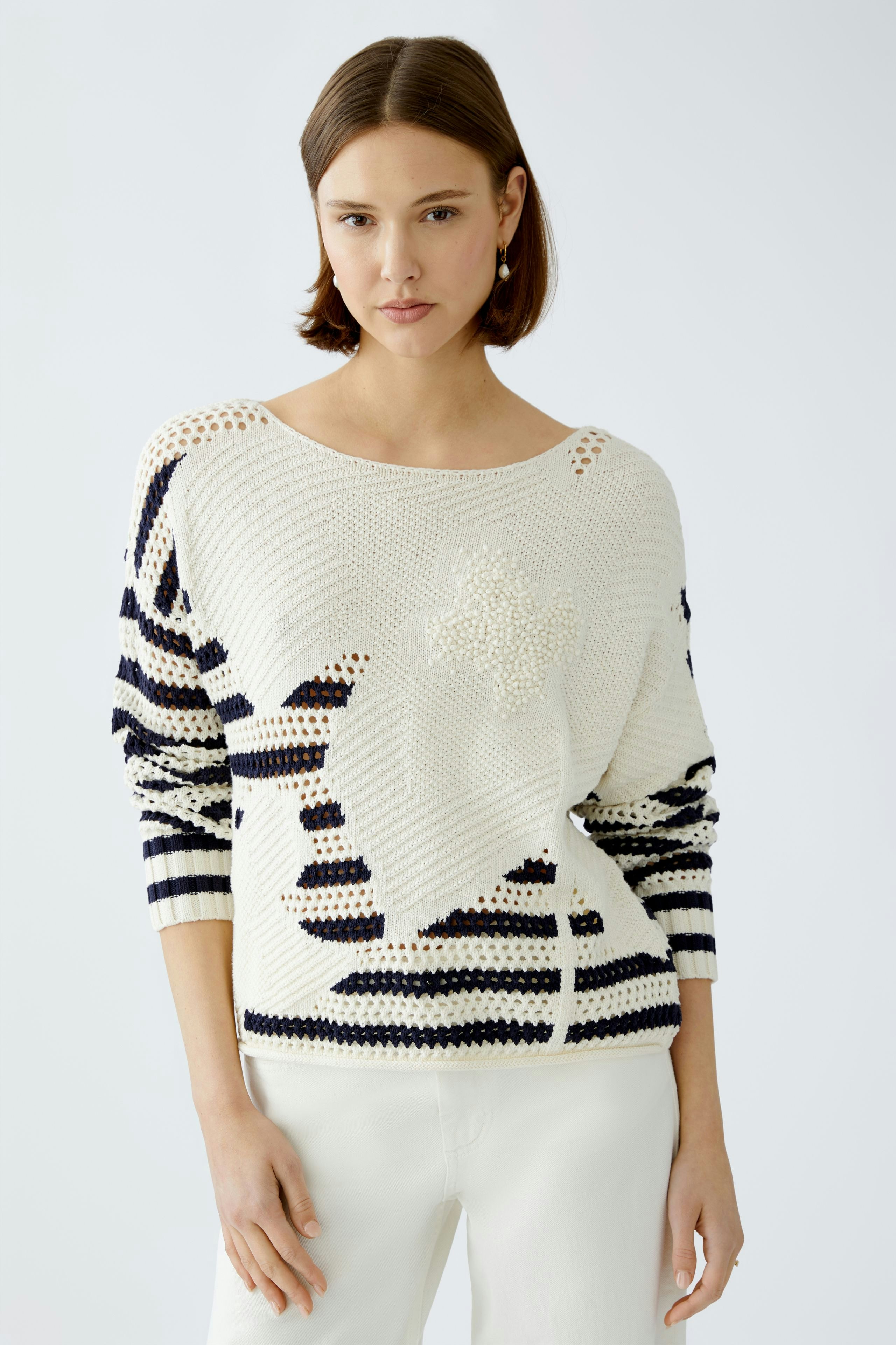 Stylish women's pullover: A woman in a cream and navy striped pullover with unique detailing.