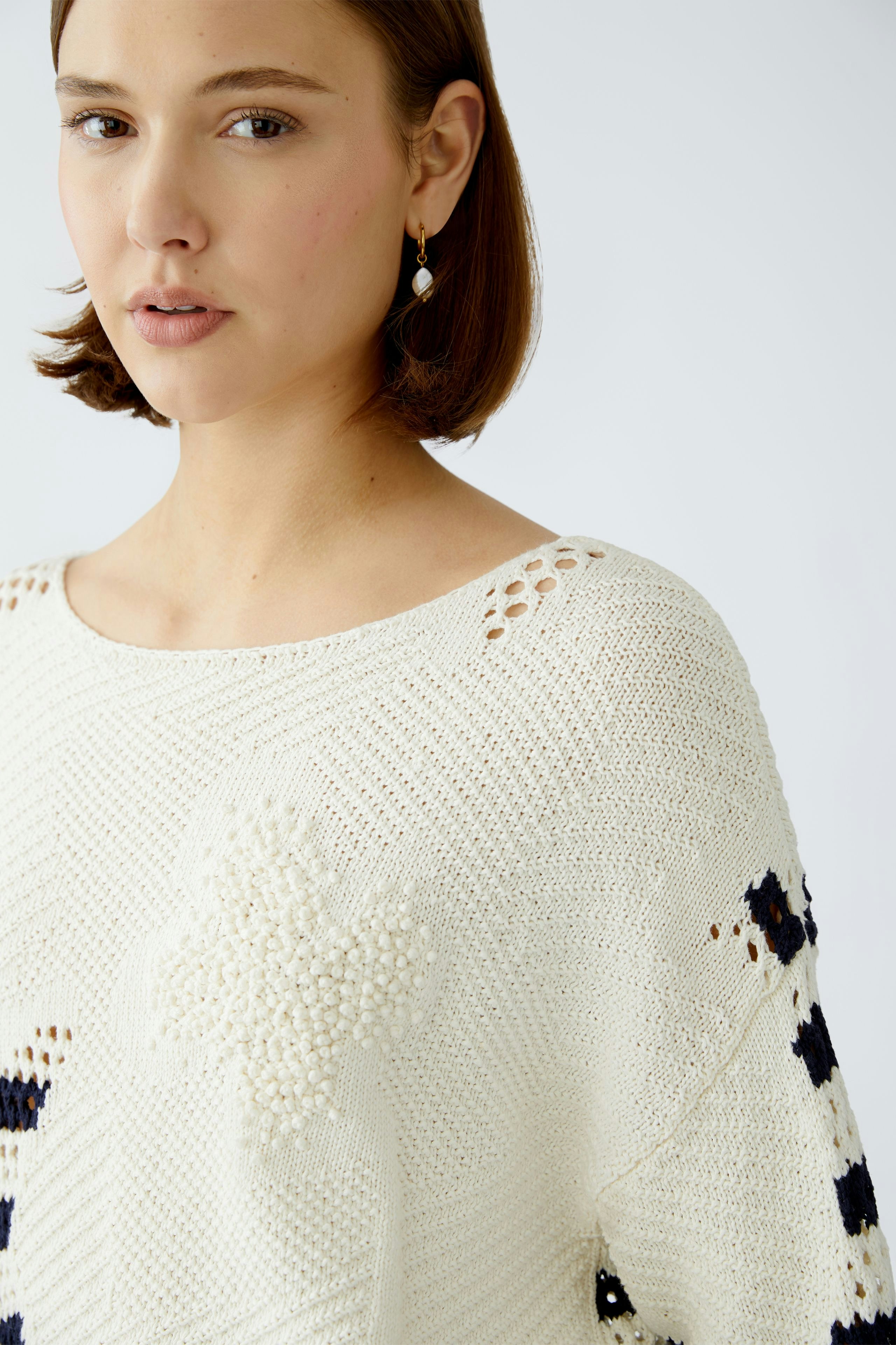 Stylish women's pullover: A woman in a cream pullover with textured details and a relaxed fit.
