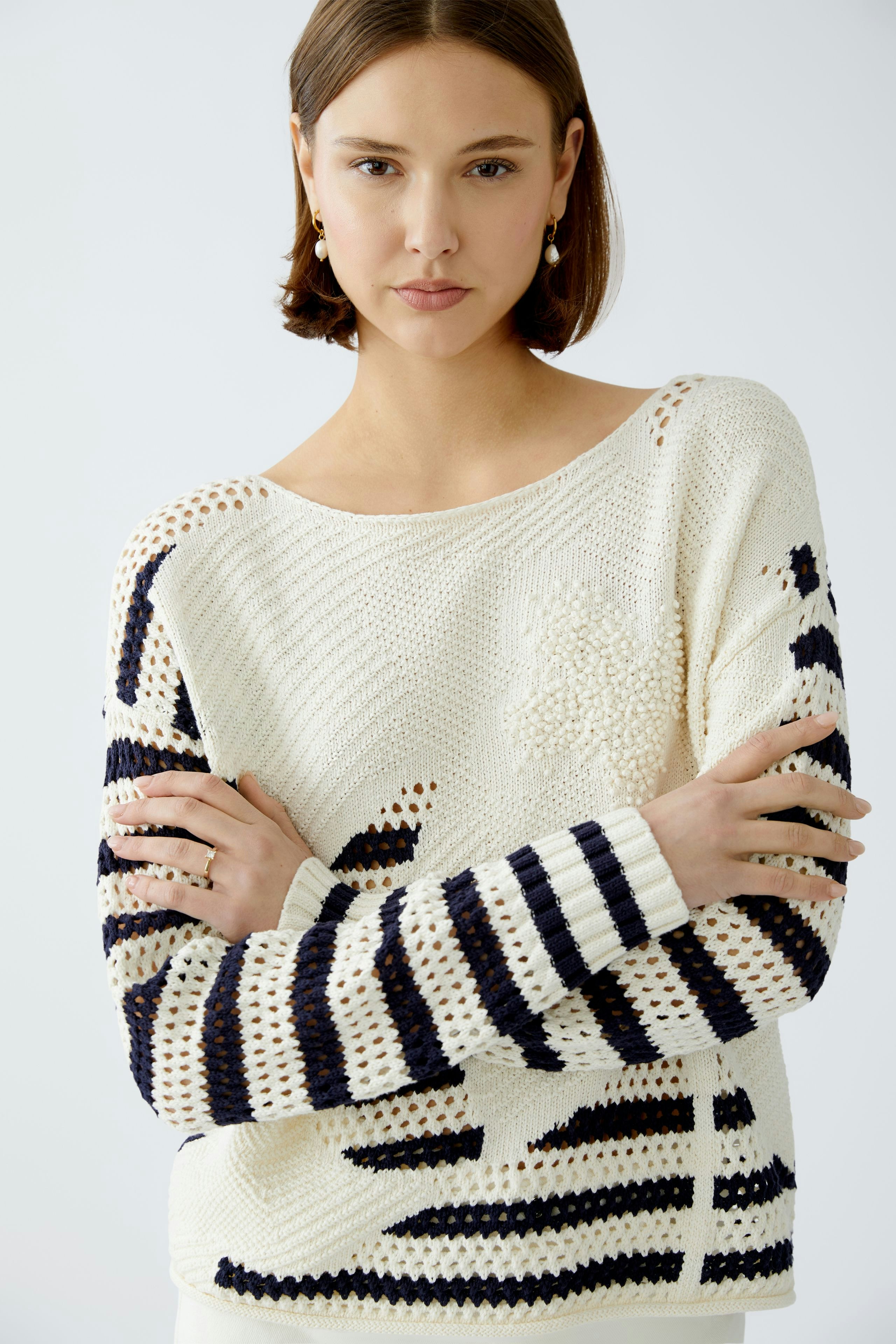 Stylish women's pullover: A woman in a cream pullover with navy stripes, exuding casual elegance.
