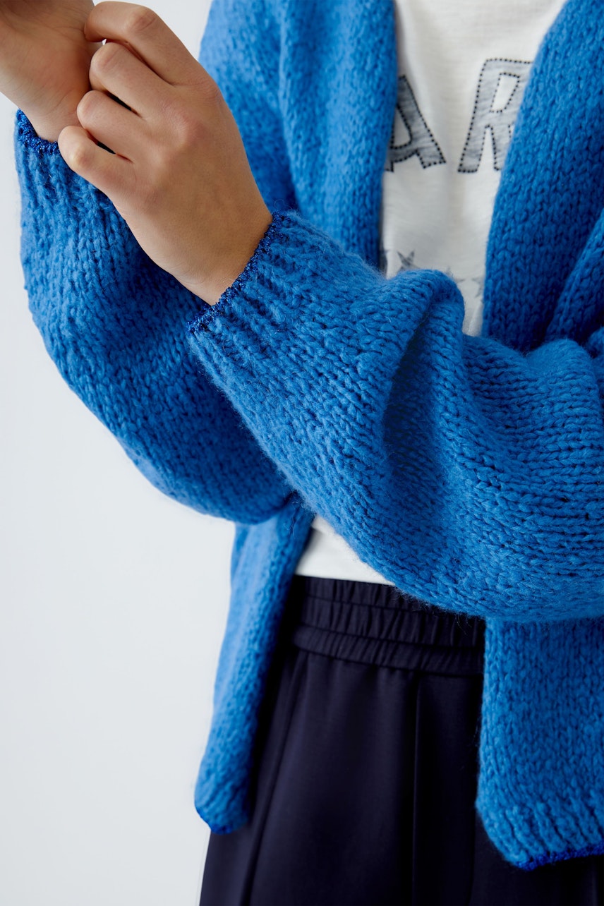 Stylish women's cardigan: A woman in a vibrant blue knitted cardigan, perfect for layering.