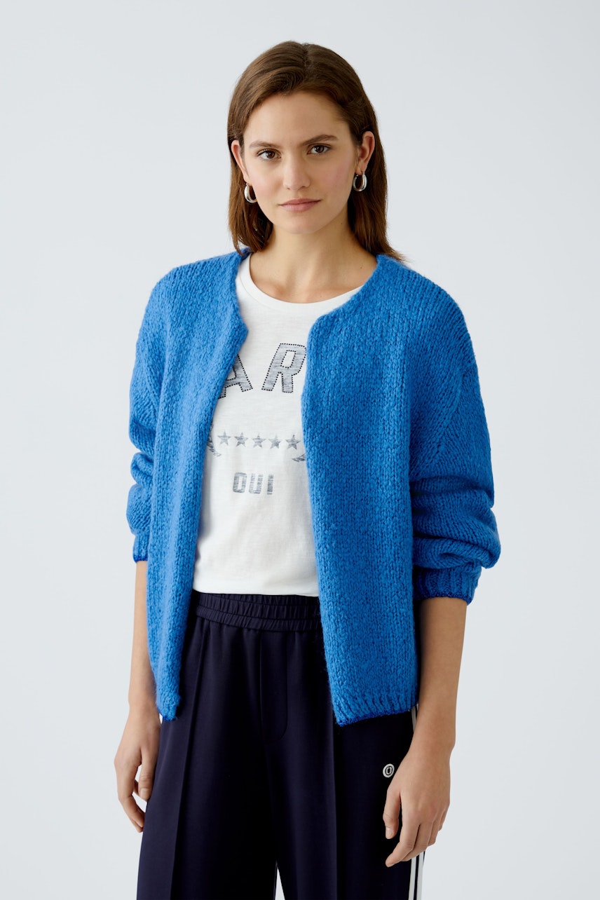 Stylish women's cardigan: A woman in a vibrant blue cardigan over a white tee, exuding casual elegance.