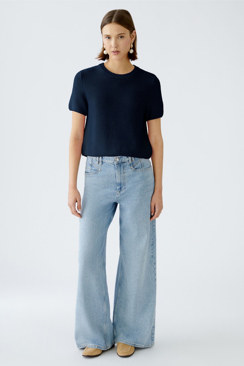 Modern women's pullover: A woman in a navy pullover paired with light blue wide-leg jeans.