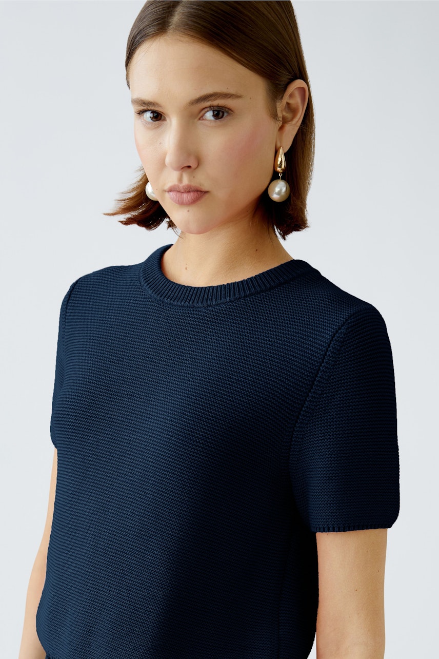 Modern women's pullover: A woman in a navy short-sleeve pullover with a textured finish.