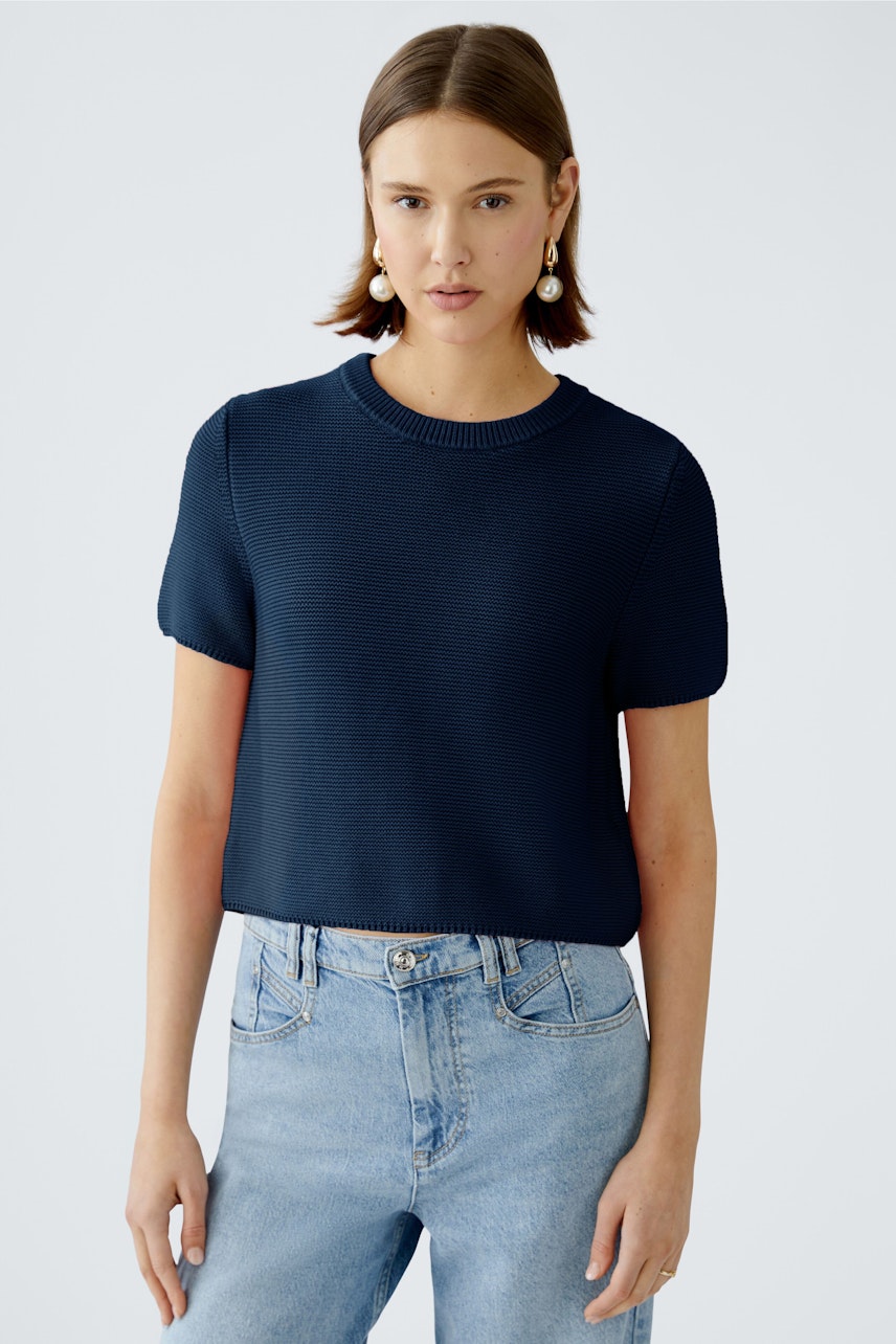 Stylish women's pullover: A woman in a navy short-sleeve pullover paired with light blue jeans.