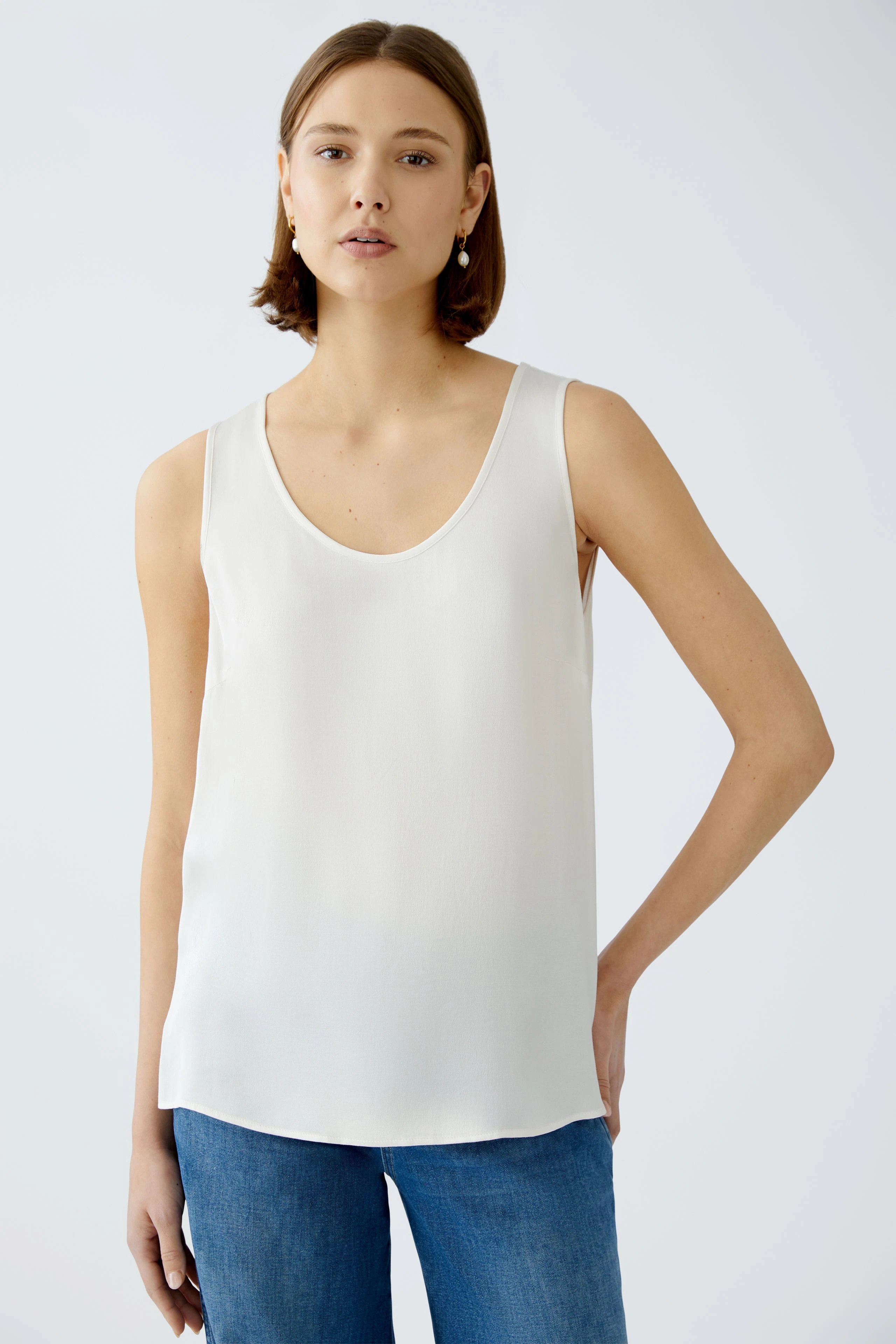 Elegantes Damen-Top: Frau trägt ein schlichtes, ärmelloses, weißes Top, ideal für den Sommer.