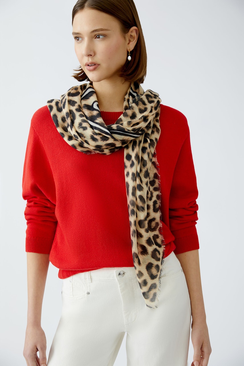 Stylish women's scarf: A woman elegantly draped in a leopard print scarf, enhancing her red pullover.