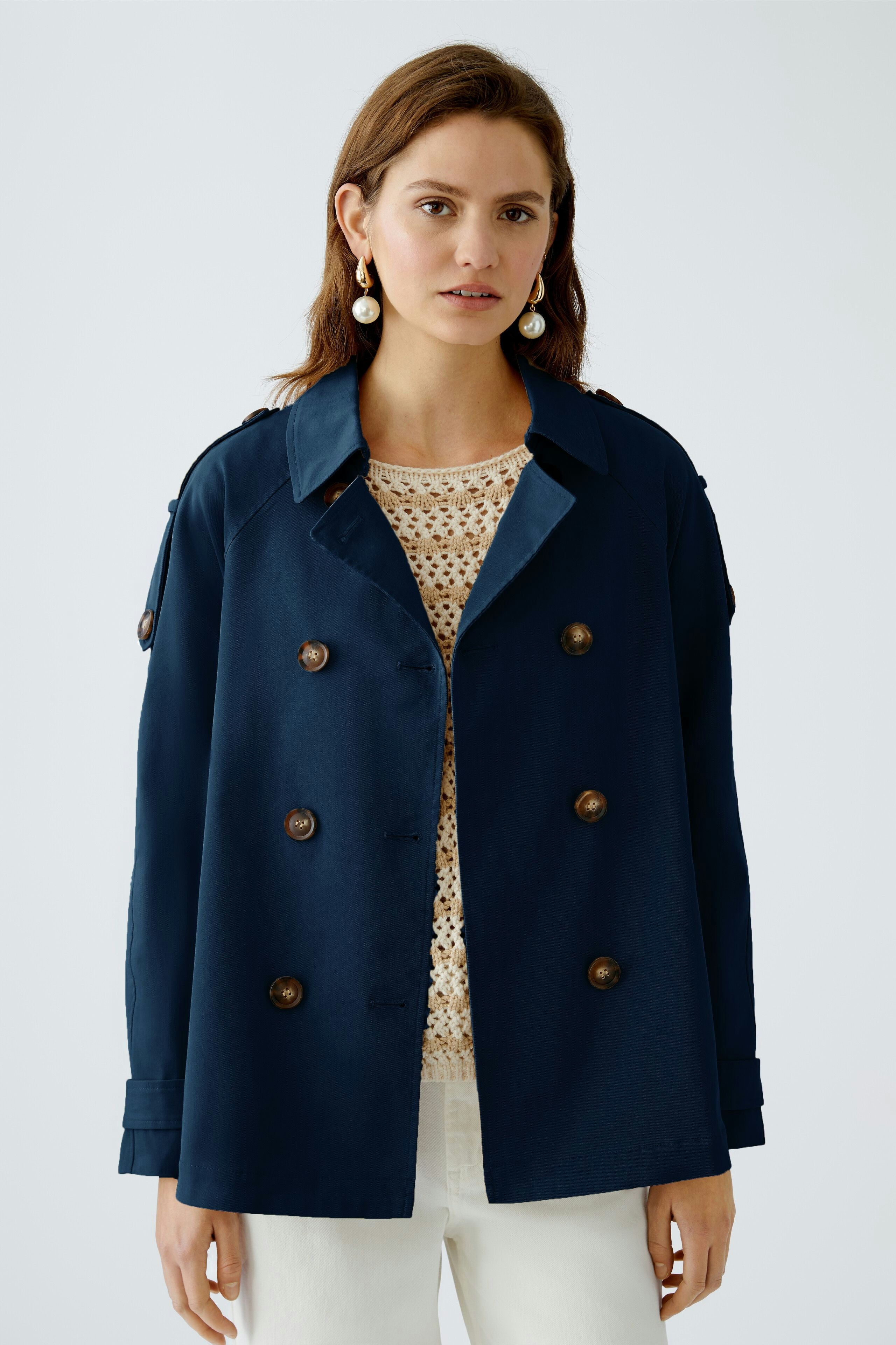 Stylish outdoor jacket: Confident woman in a navy double-breasted jacket over a light pullover.