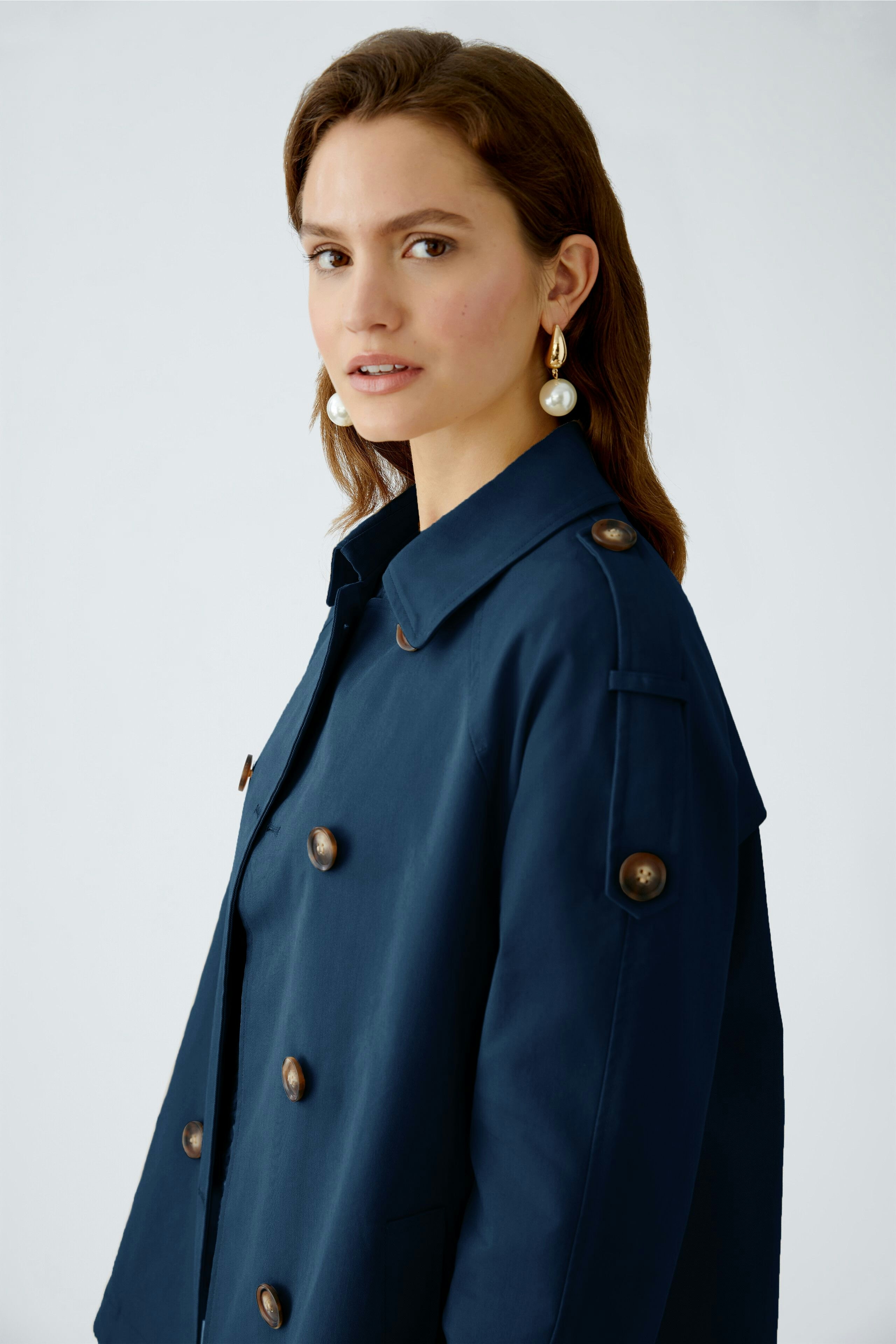 Stylish women's outdoor jacket: A woman in a navy jacket with large buttons, exuding confidence.