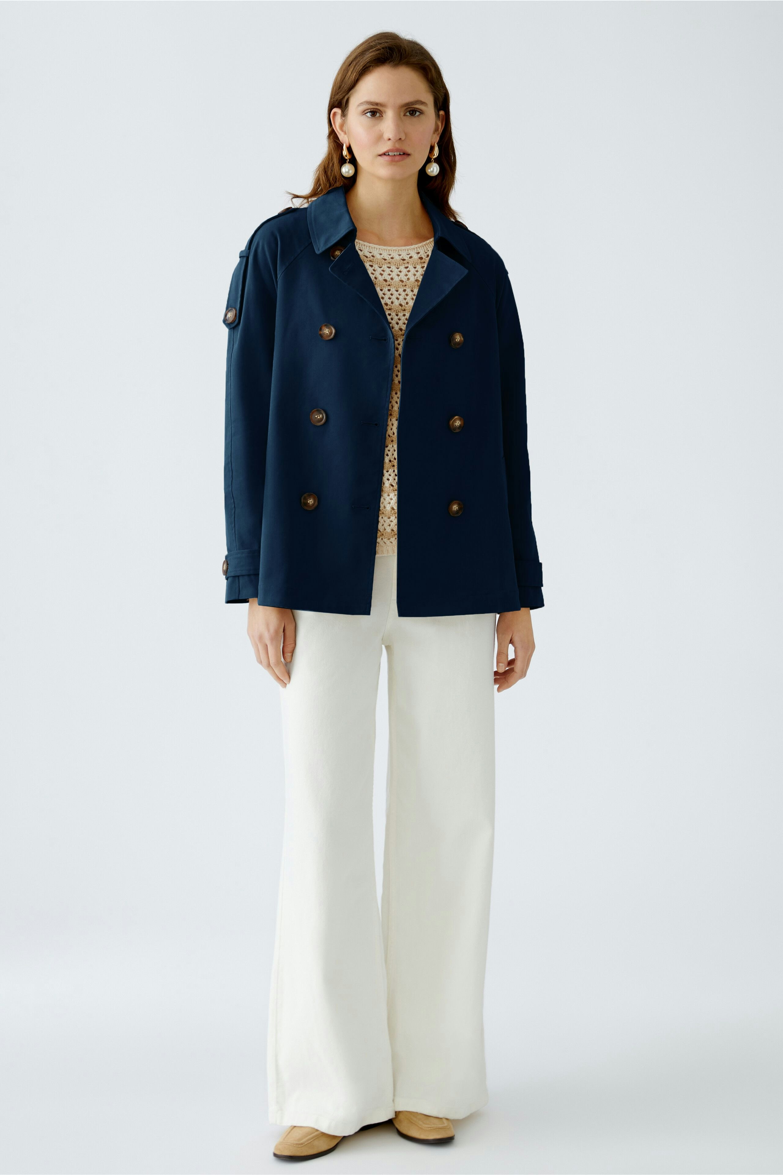 Stylish women's outdoor jacket: A woman in a navy double-breasted jacket paired with white pants.