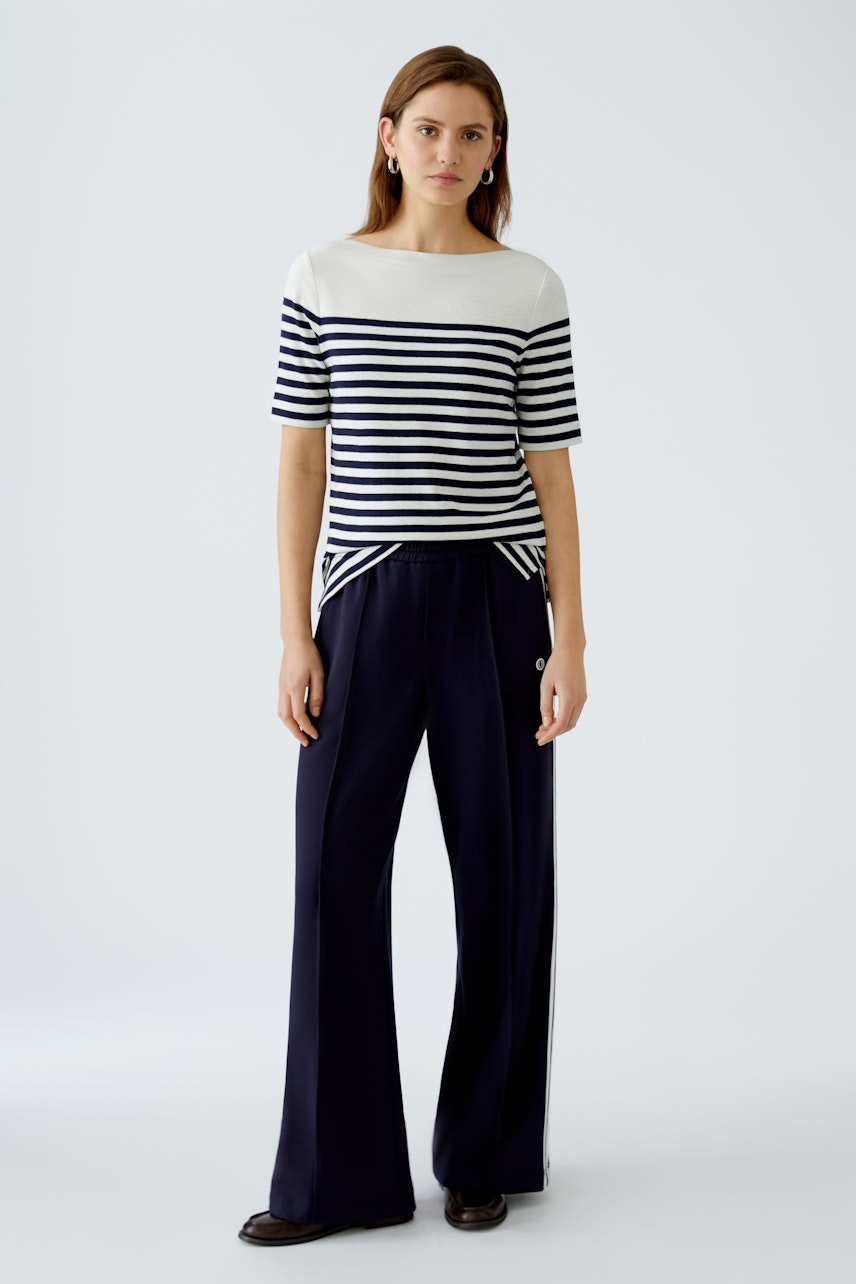 Stylish women's long-sleeve shirt: A woman in a striped pullover, paired with elegant navy trousers.