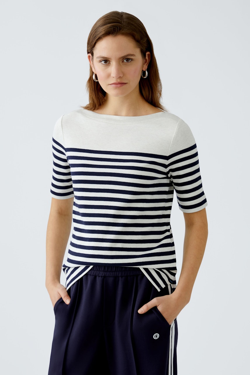 Stylish women's long-sleeve shirt: A woman in a striped top with a relaxed fit and casual style.