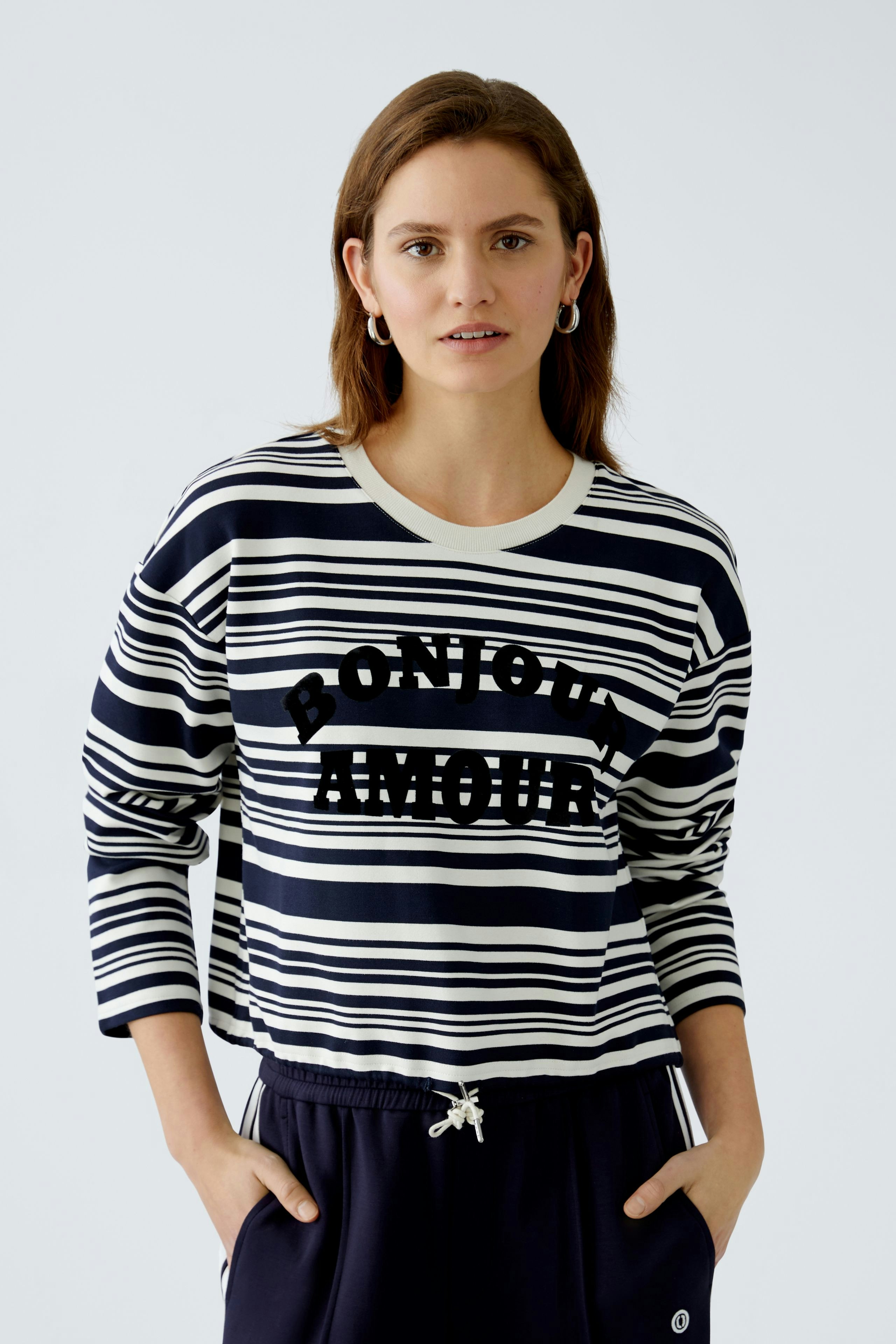 Damen-Sweatshirt: Frau in gestreiftem Pullover mit Schriftzug, lässig und modern.