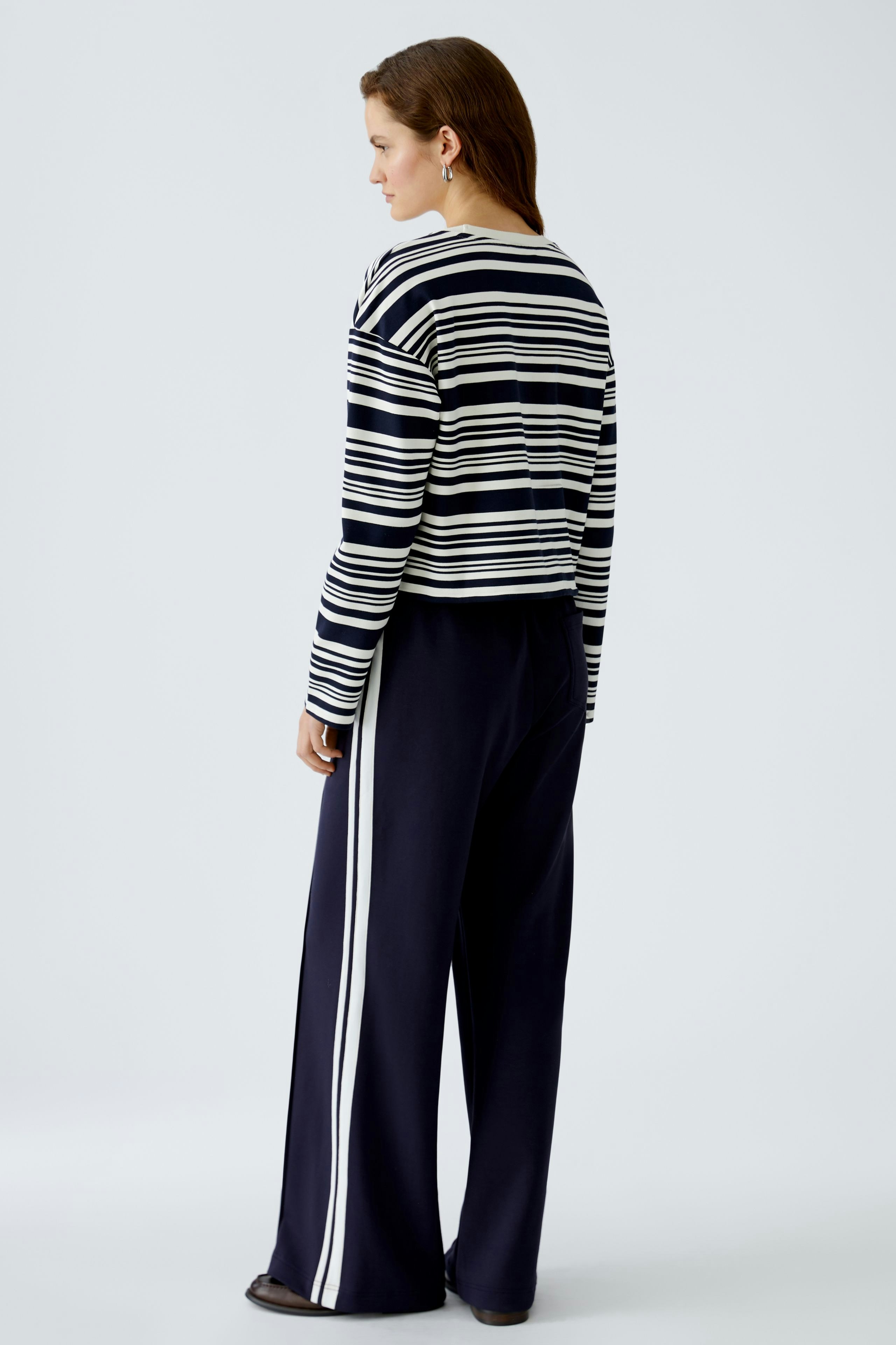 Damen-Sweatshirt: Frau in gestreiftem Pullover mit lässigem Schnitt und bequemen Hosen.