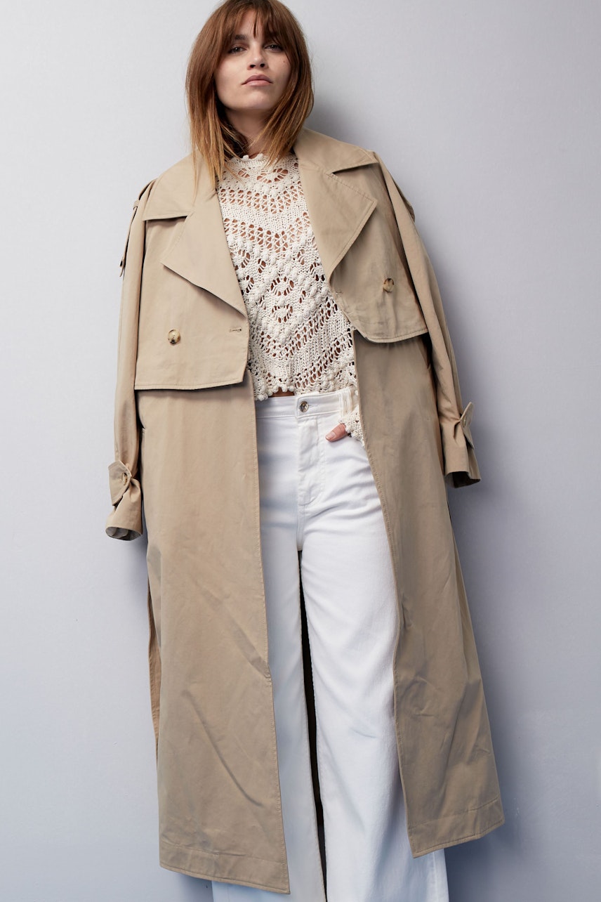 Stylish women's straight jeans: A woman in a chic outfit with a beige trench coat and white jeans.