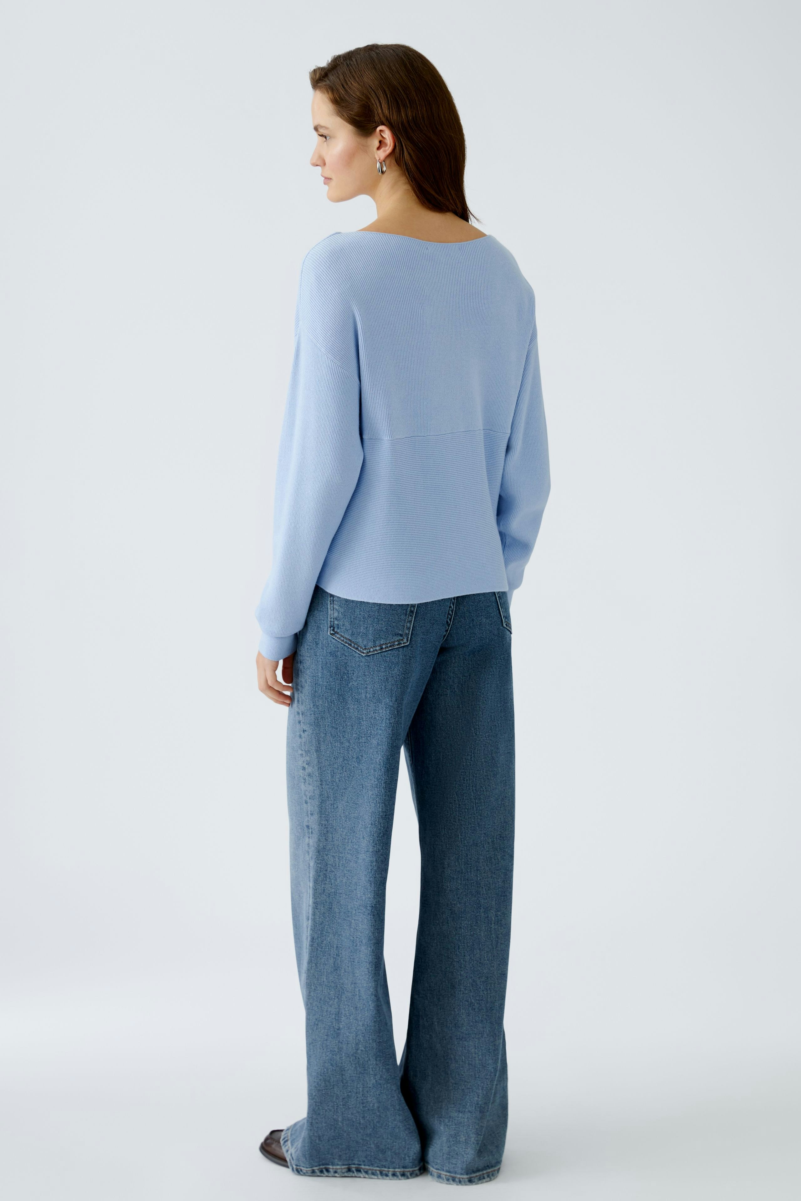 Stylish women's pullover: A woman in a light blue pullover with a relaxed fit and wide jeans.