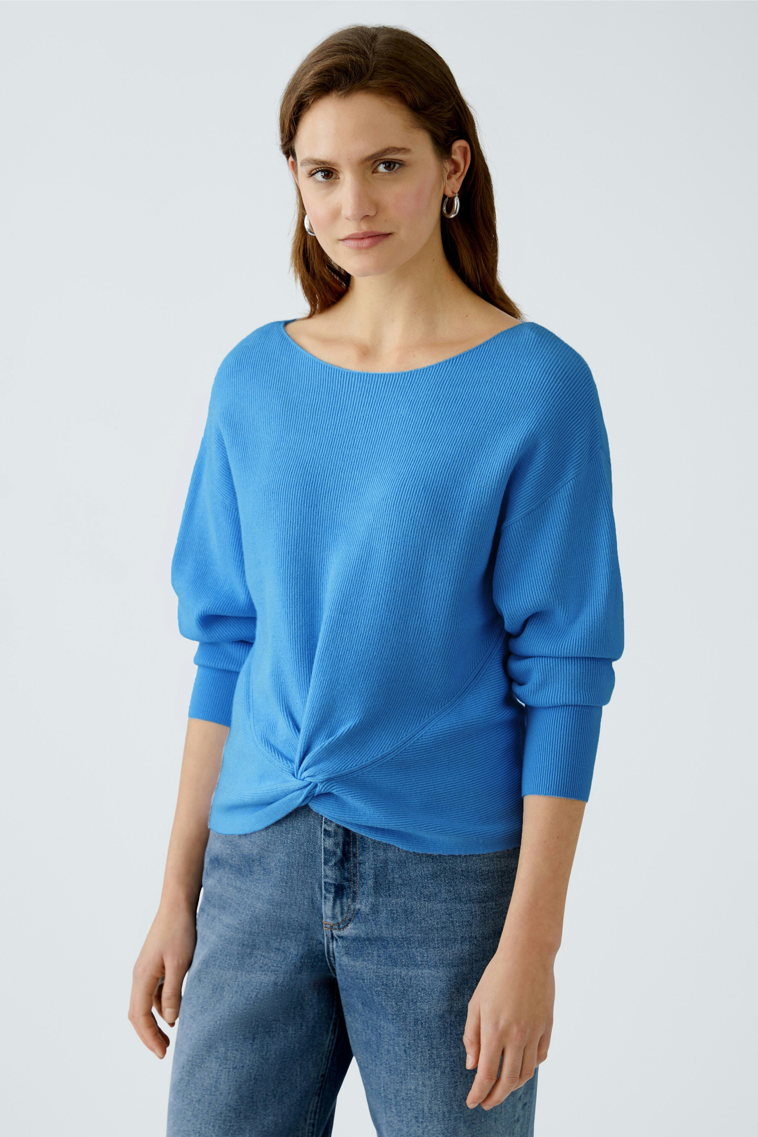 Damen-Pullover: Junge Frau in blauem, lässigem Pullover mit Knoten-Detail und lockerer Passform.