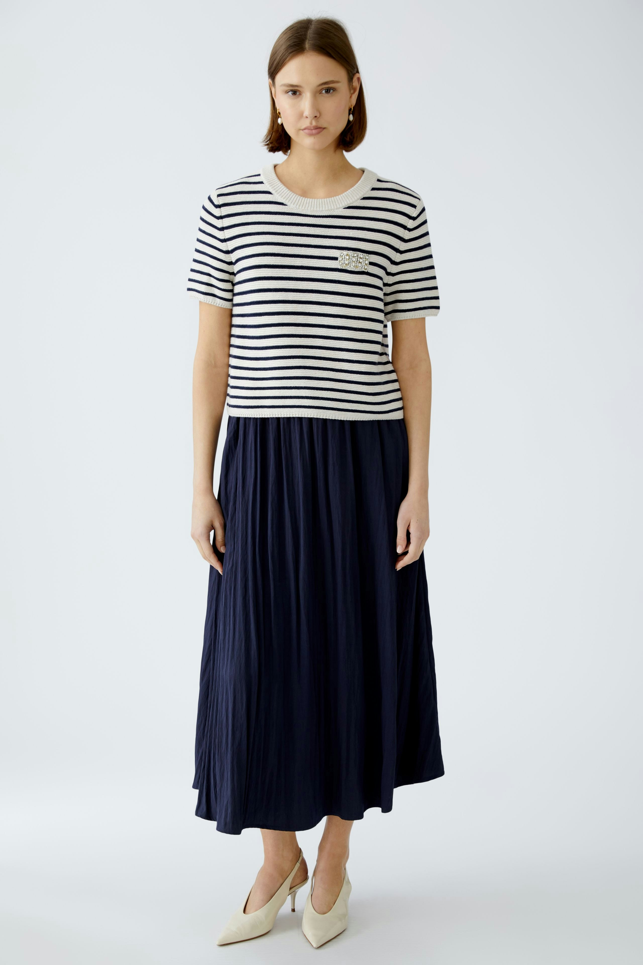 Stylish women's pullover: A woman in a striped top paired with a flowing navy skirt.