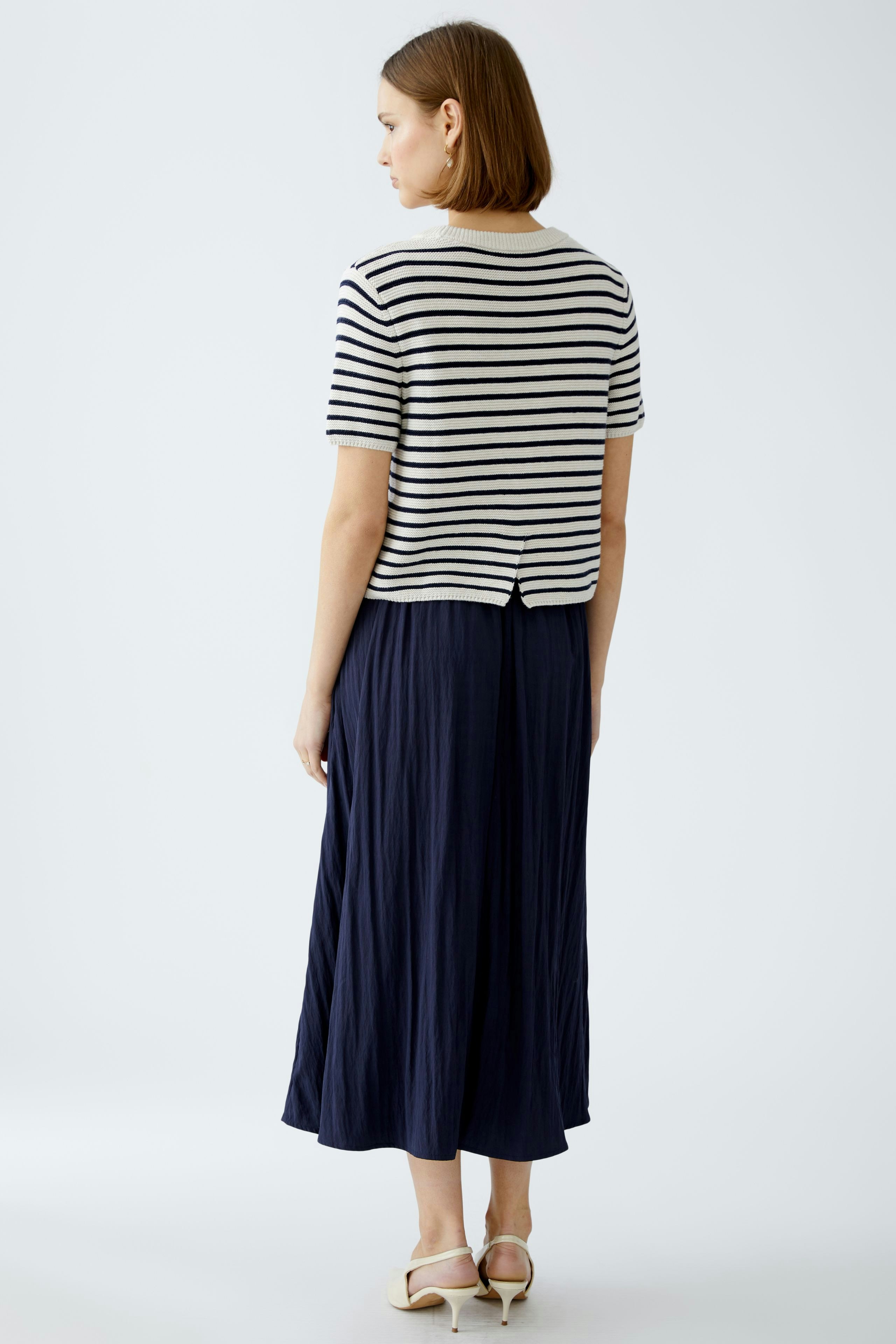 Stylish women's pullover: A woman in a striped pullover and flowing navy skirt, showcasing a chic look.