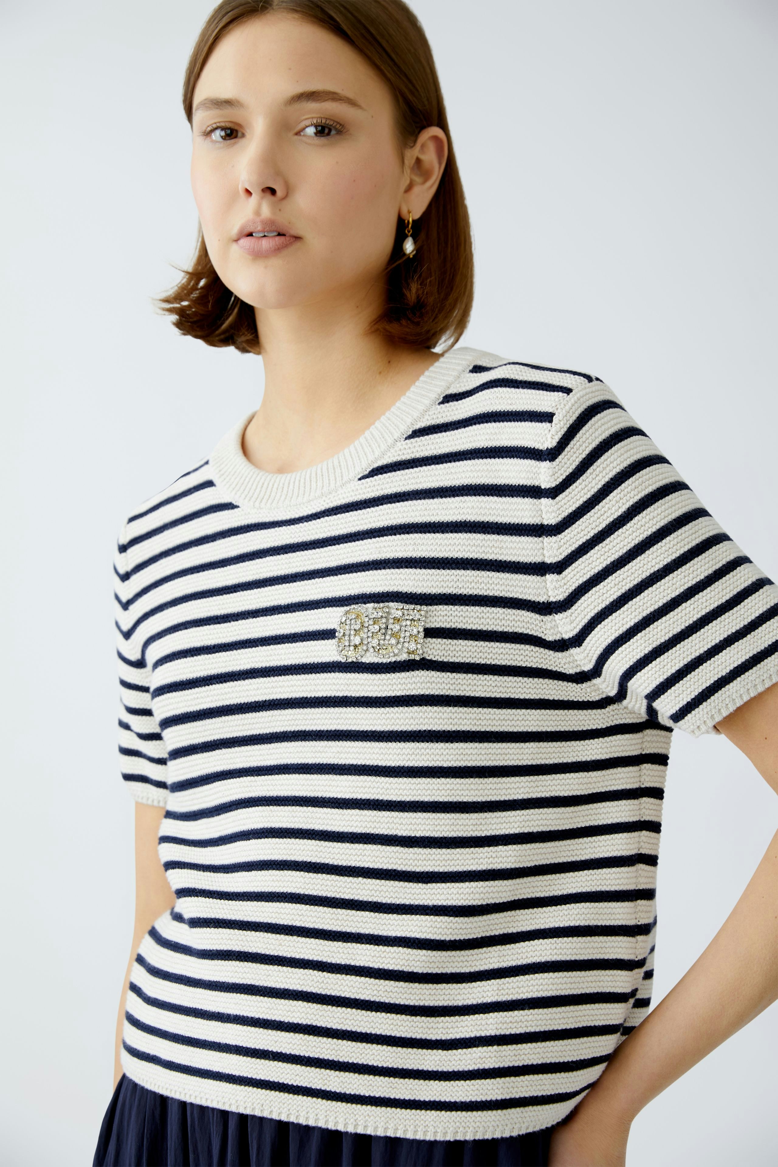 Stylish women's pullover: A woman in a striped pullover with a decorative brooch, exuding casual elegance.