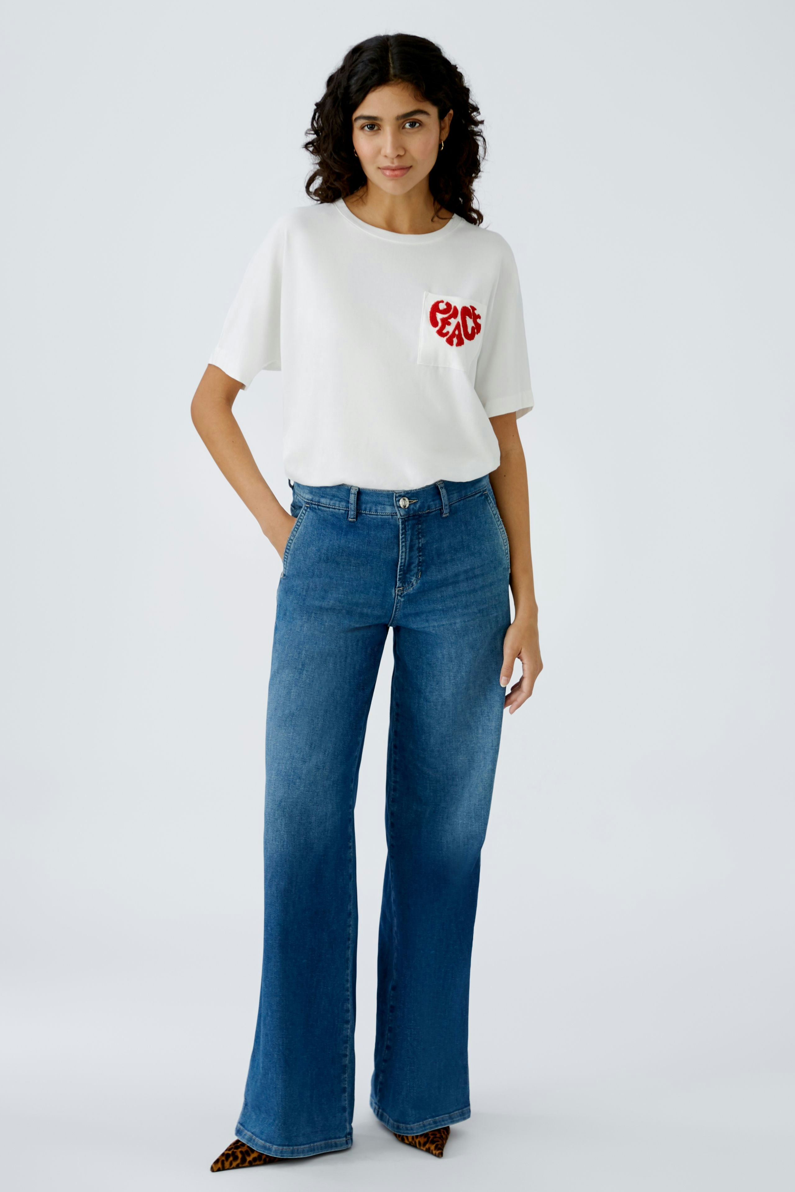 Damen-T-Shirt in Weiß mit rotem Herz-Design, lässig kombiniert mit blauen Jeans.