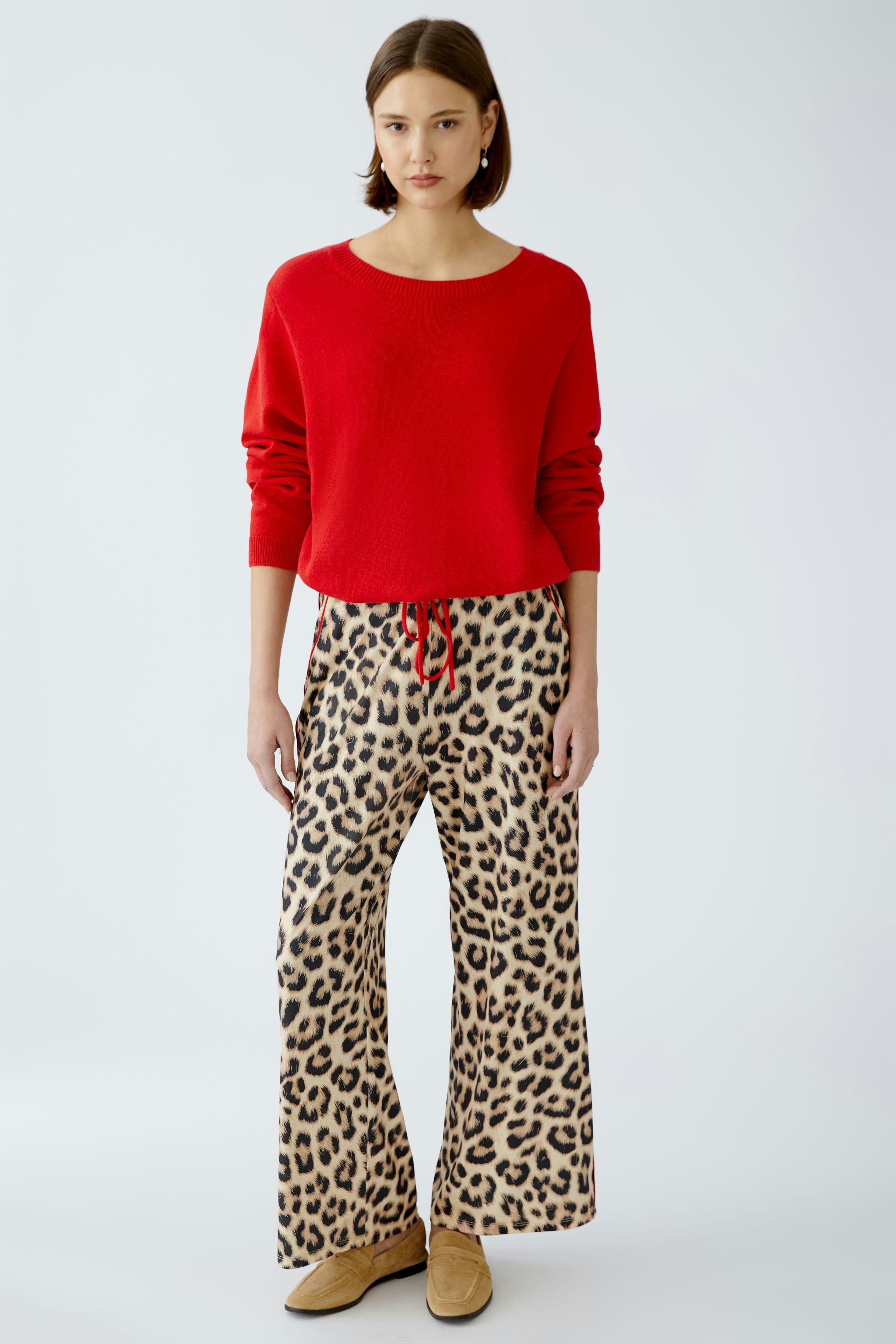 Stylish women's pants: A woman in leopard print trousers and a red pullover stands confidently.