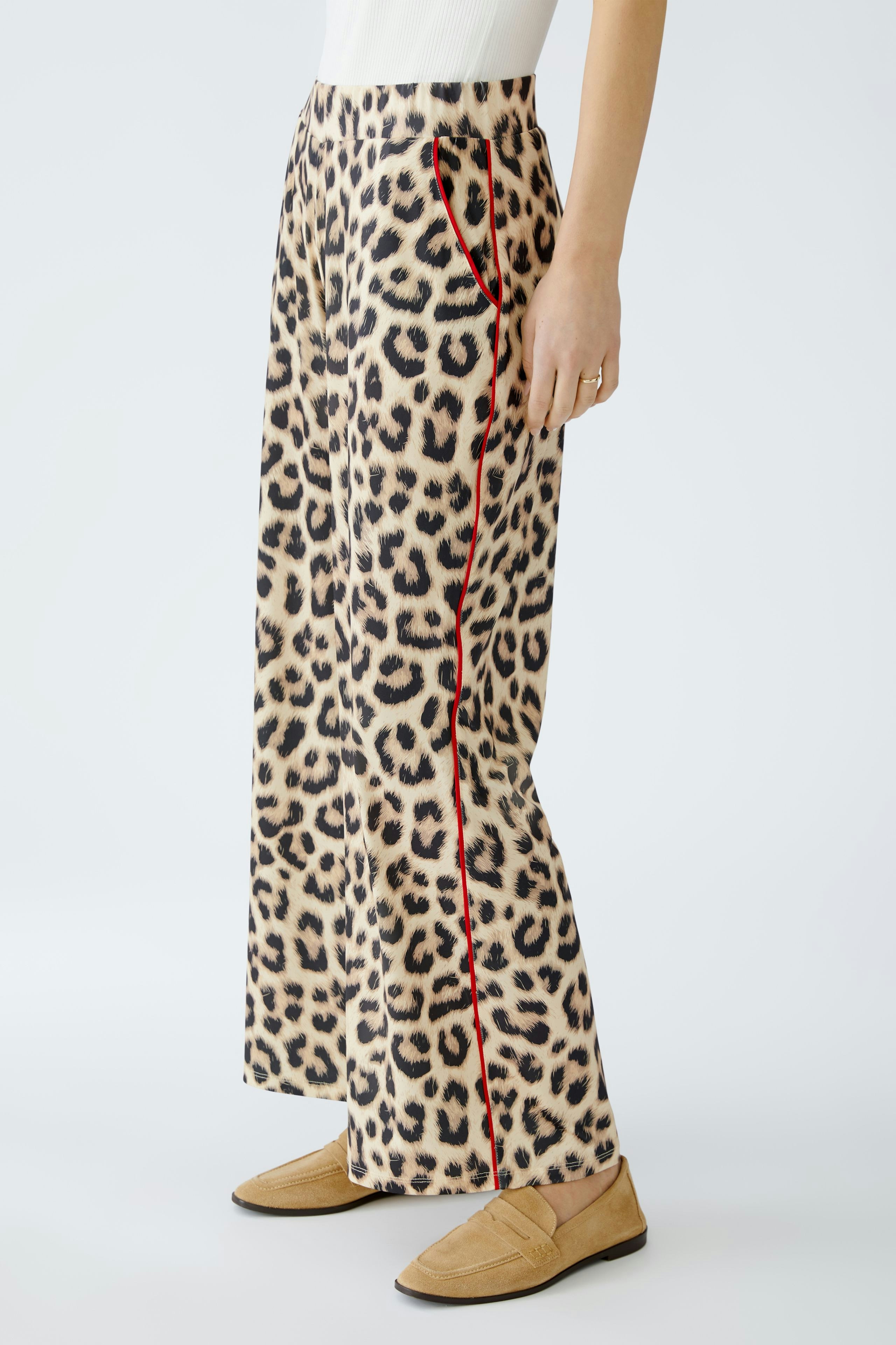 Stylish women's trousers: A woman in leopard print pants with red accents stands confidently.