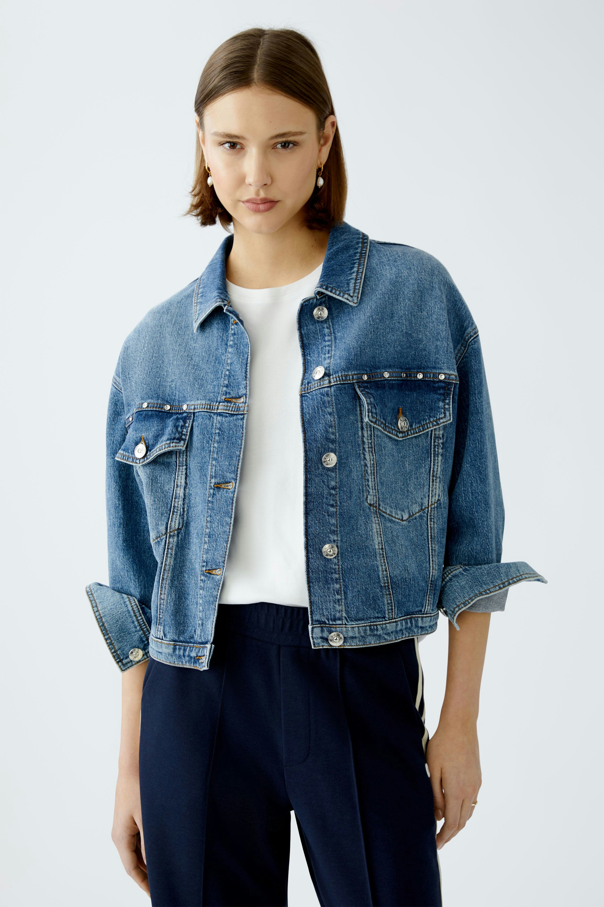 Stylish women's denim jacket: A woman in a cropped blue jacket with pockets and a relaxed fit.