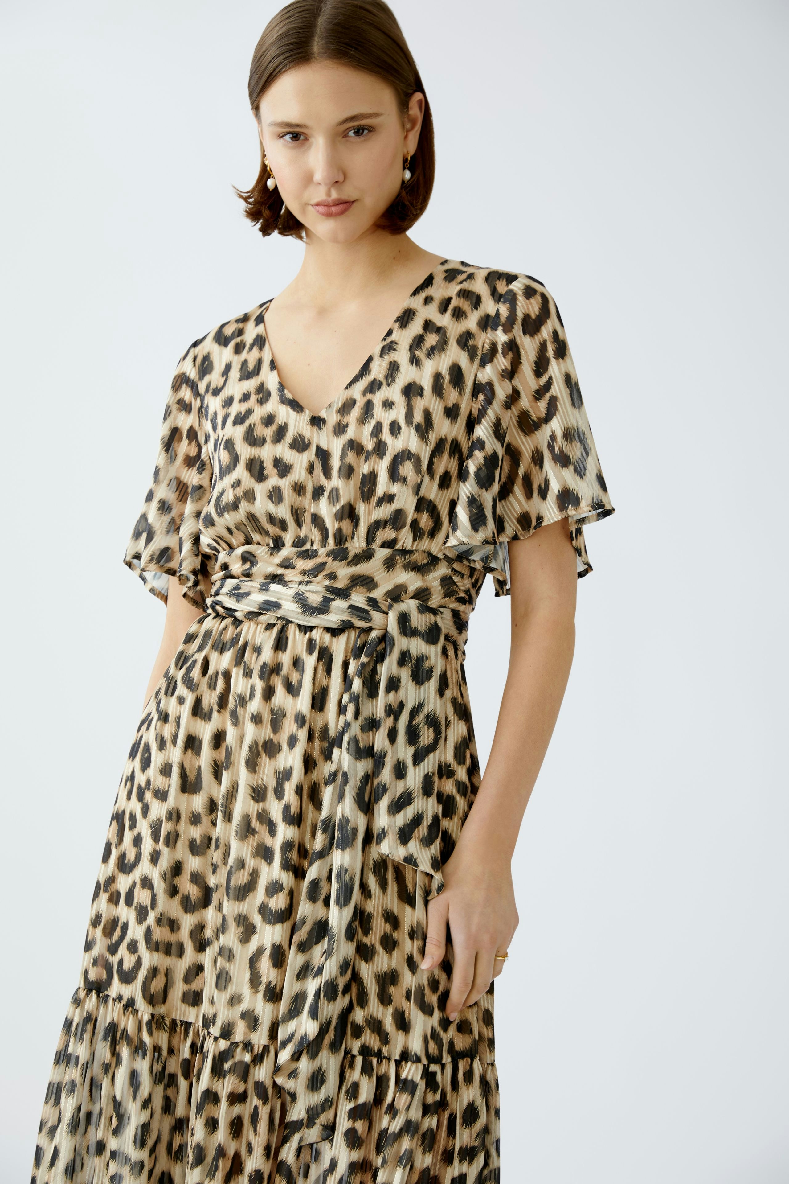 Elegant maxi dress: Woman in a stylish leopard print dress with flowing sleeves and a flattering silhouette.