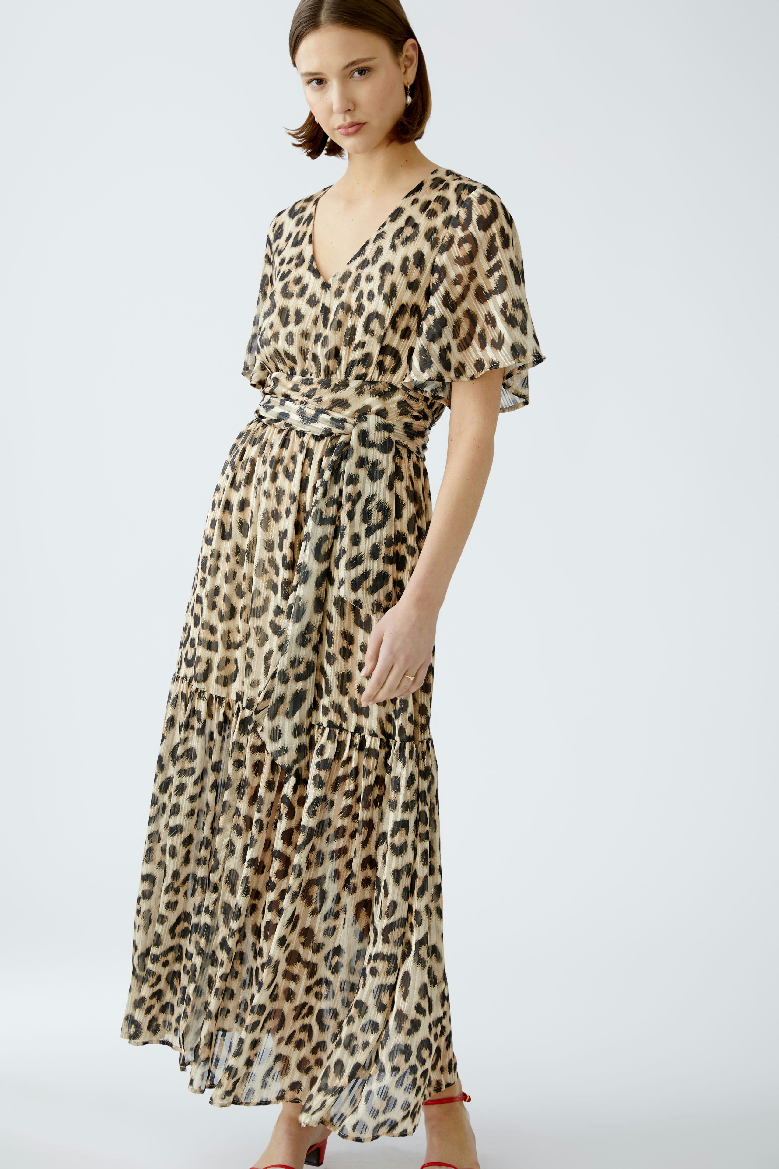 Elegant maxi dress: Woman in a flowing leopard print dress with a flattering wrap design.