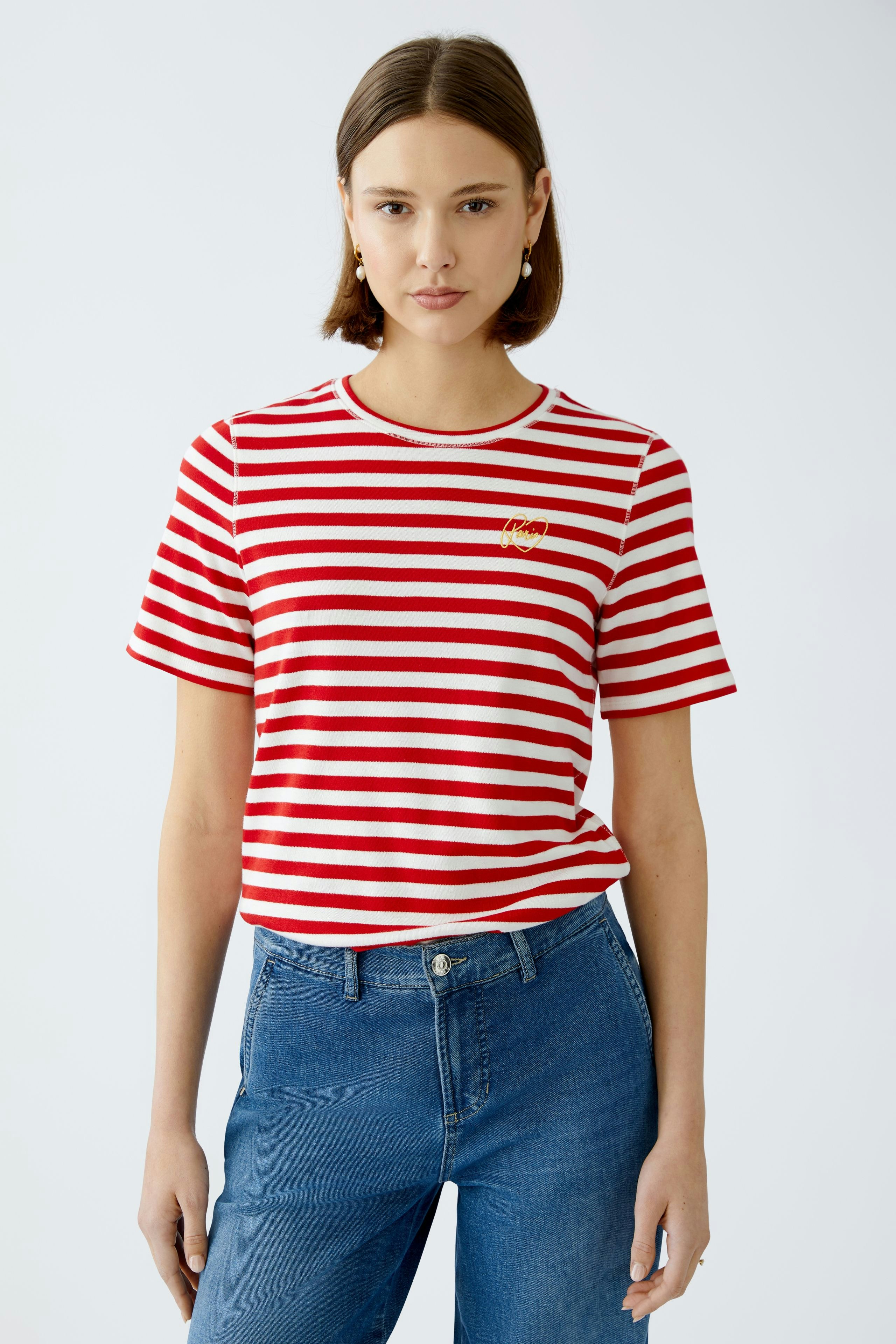 Stylish women's T-shirt: A woman in a red and white striped tee with a logo, paired with blue jeans.